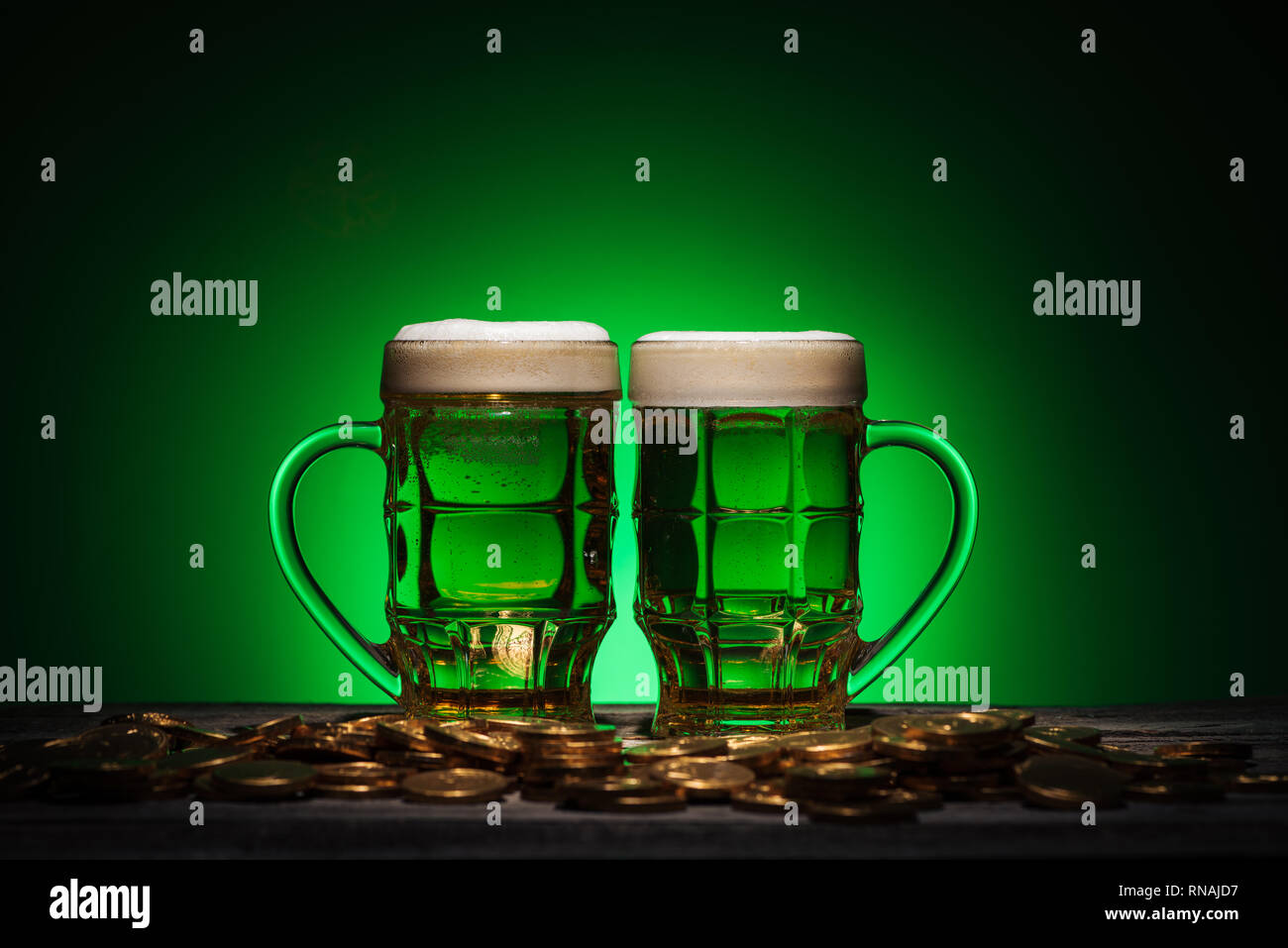 Gläser Alkohol Bier stehend in der Nähe von Golden Coins auf st patricks day auf grünem Hintergrund Stockfoto