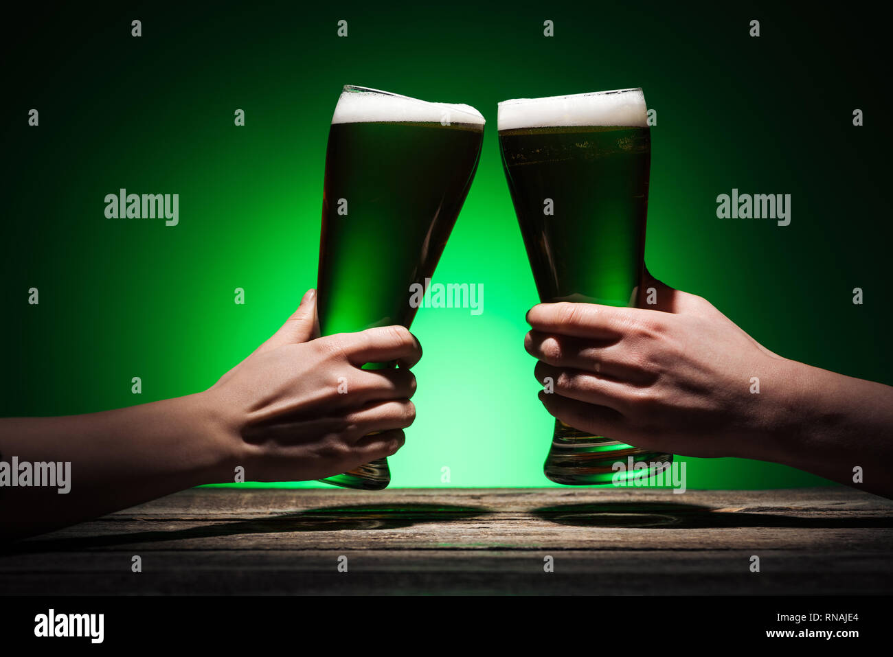 7/8-Ansicht von Männern Toasten mit Brille von Irish Ale auf st patricks day auf grünem Hintergrund Stockfoto