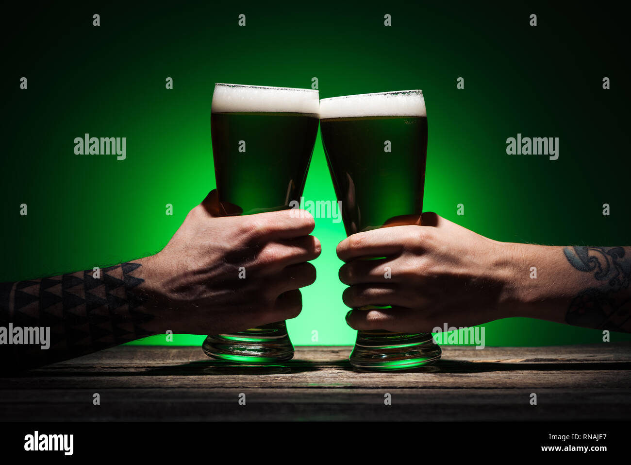7/8-Ansicht von Männern klirren mit Brille von Irish Ale auf st patricks day auf grünem Hintergrund Stockfoto