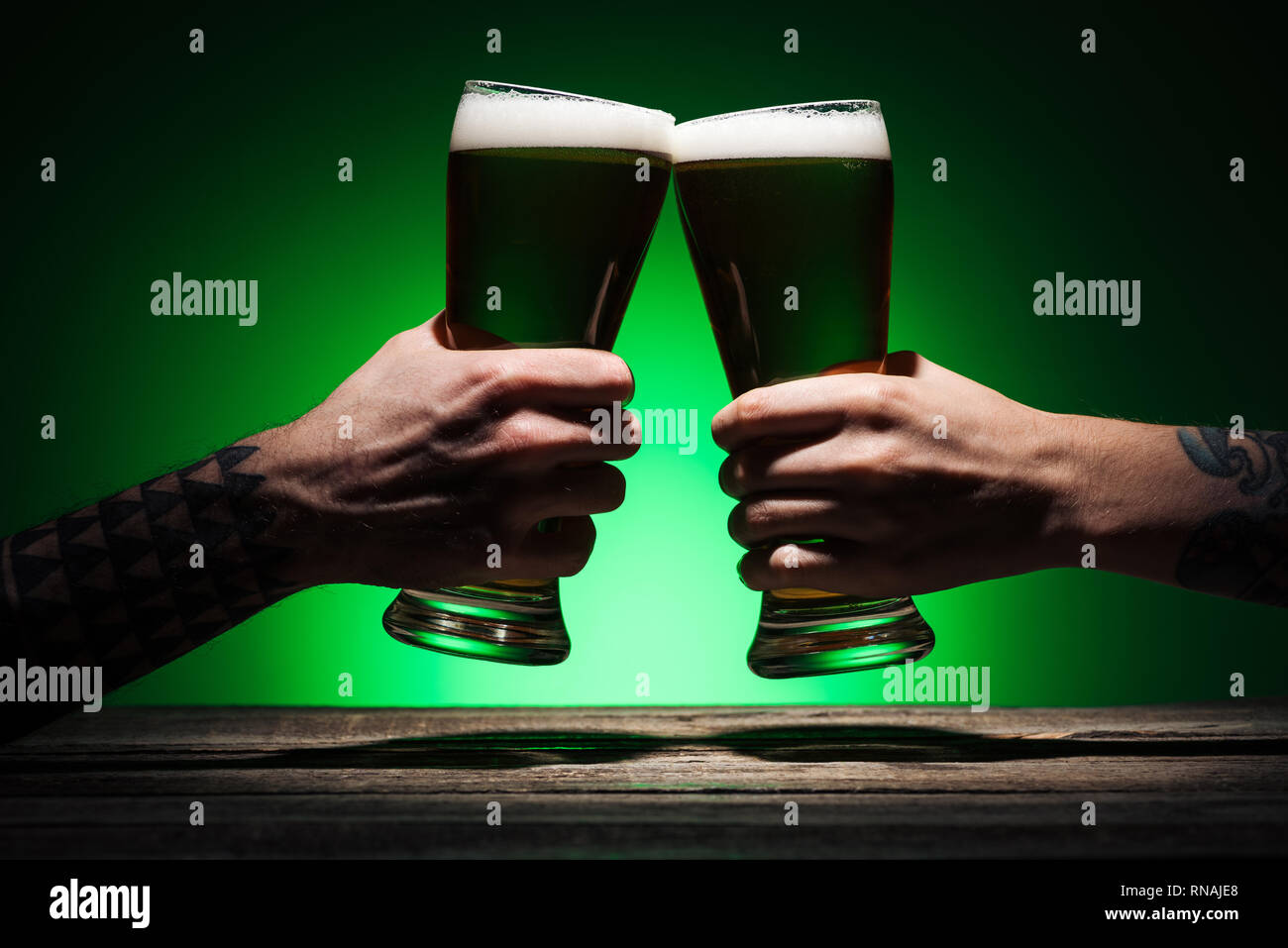 7/8-Ansicht von Männern mit Gläser Klirren der irischen Bier auf st patricks day auf grünem Hintergrund Stockfoto