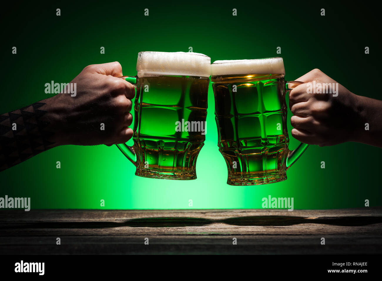 7/8-Ansicht von männlichen Freunden klirren mit Brille von Irish Ale auf st patricks day auf grünem Hintergrund Stockfoto