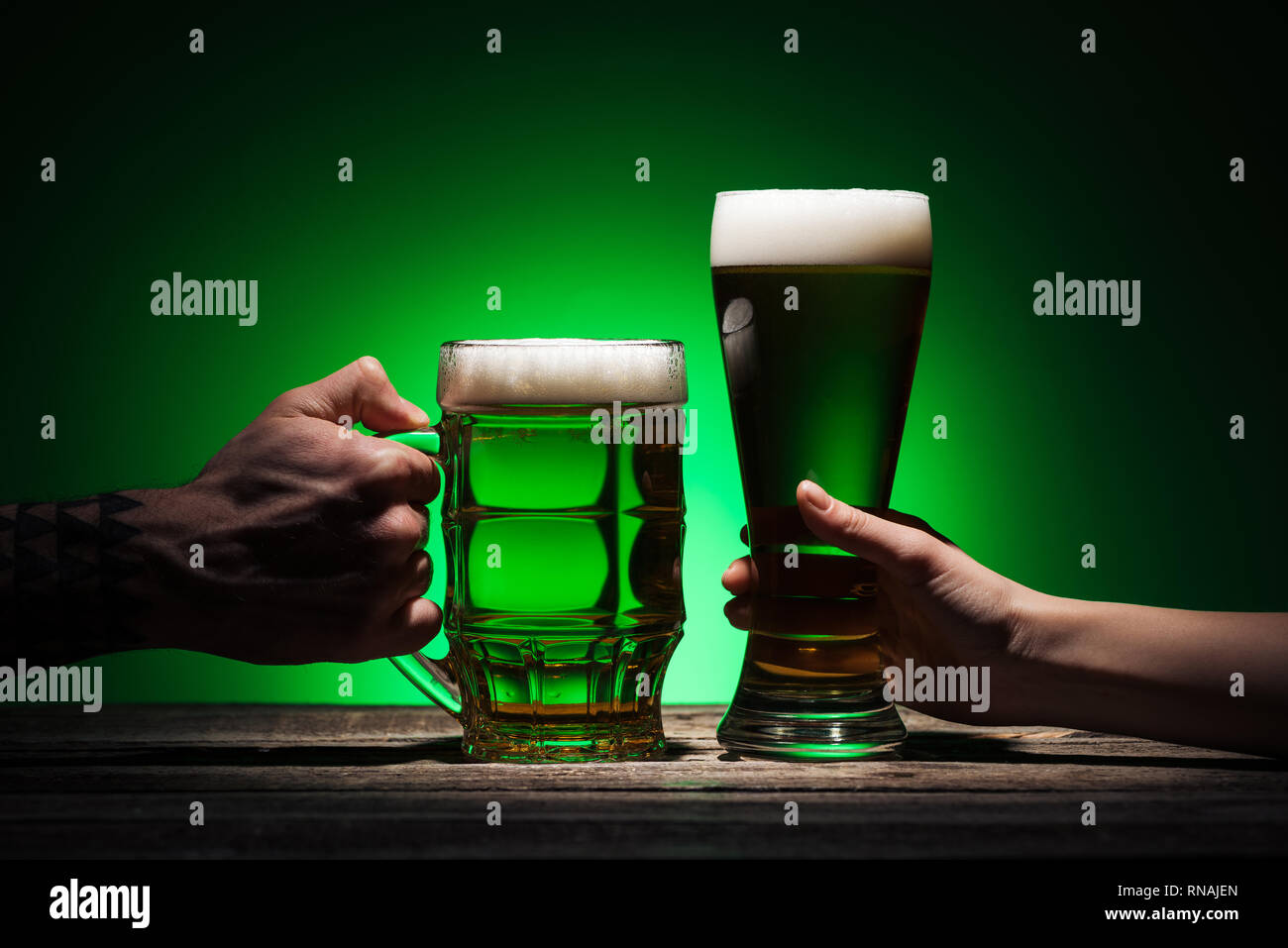 7/8-Ansicht der Männer halten Gläser Grün Bier auf st patricks day auf grünem Hintergrund Stockfoto