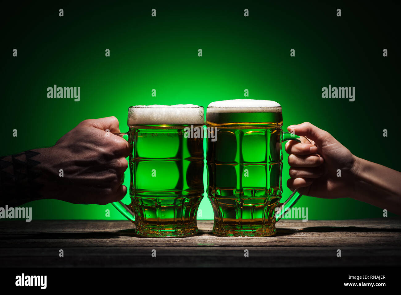 Anzeigen von Freunden halten Gläser Bier auf st patricks day auf grünem Hintergrund 7/8 Stockfoto