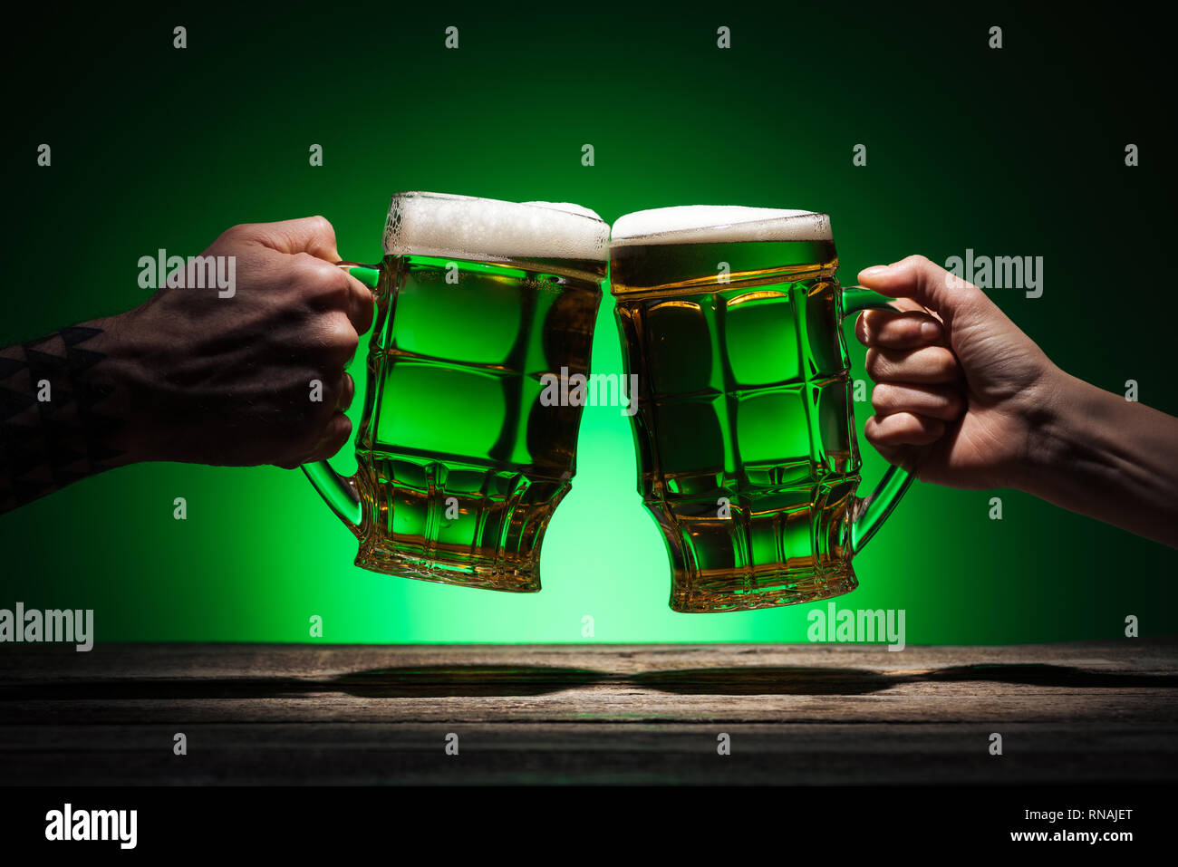 7/8-Ansicht von Freunden Toasten mit Gläsern Bier auf st patricks day auf grünem Hintergrund Stockfoto