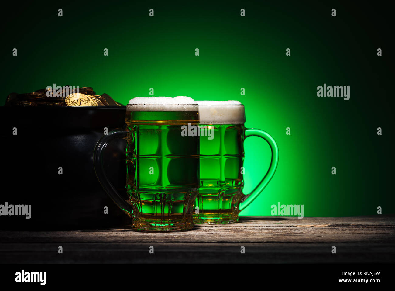 Gläser Ale in der Nähe von Topf mit Gold auf st patricks day auf grünem Hintergrund Stockfoto