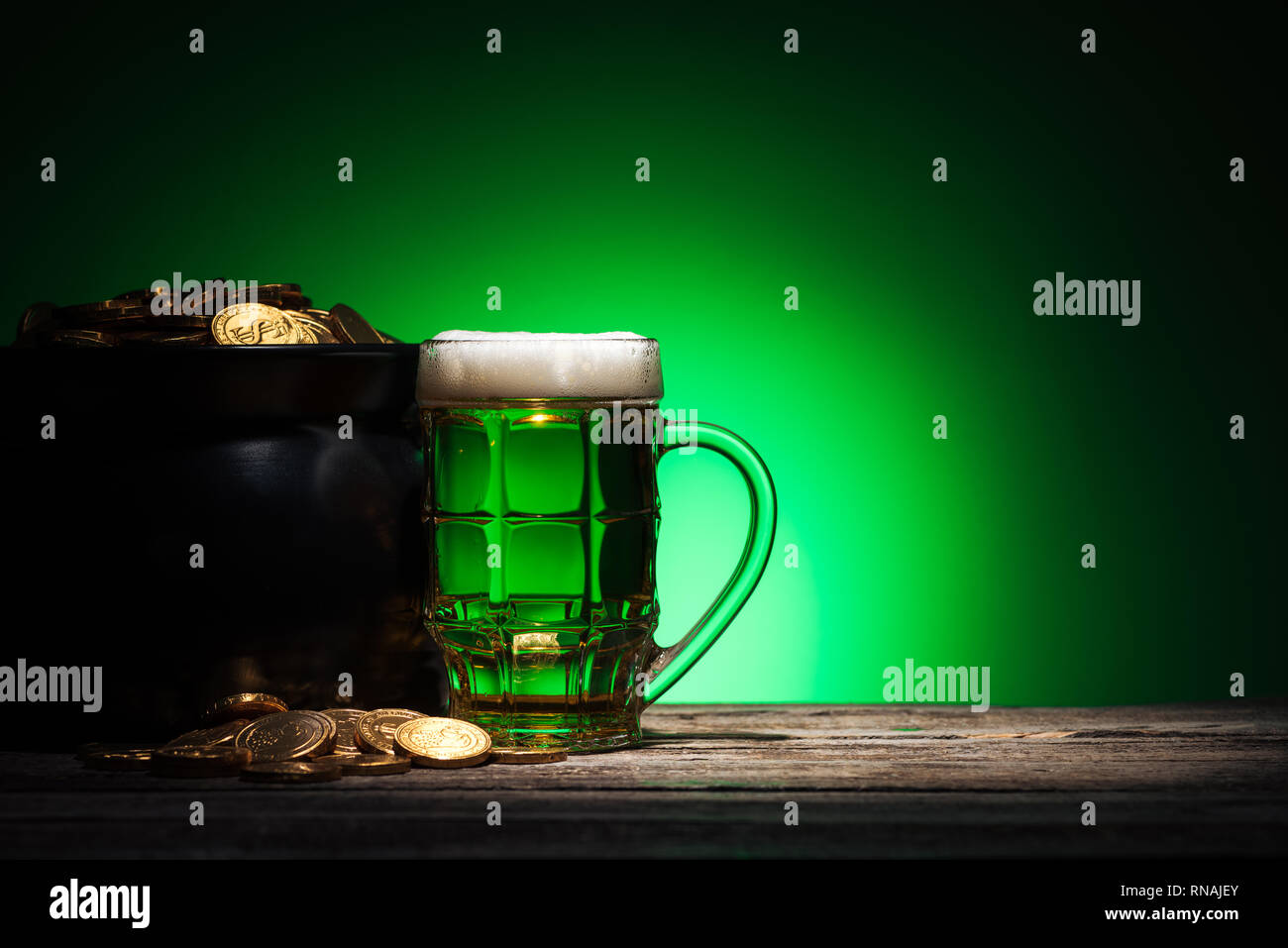 Glas Ale in der Nähe von Topf mit goldenen Münzen auf st patricks day auf grünem Hintergrund Stockfoto