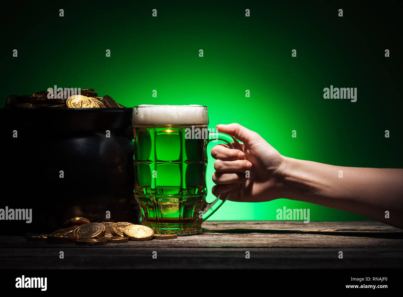 7/8-Ansicht von man toasten Glas irisches Bier mit Pot of Gold auf grünem Hintergrund Stockfoto