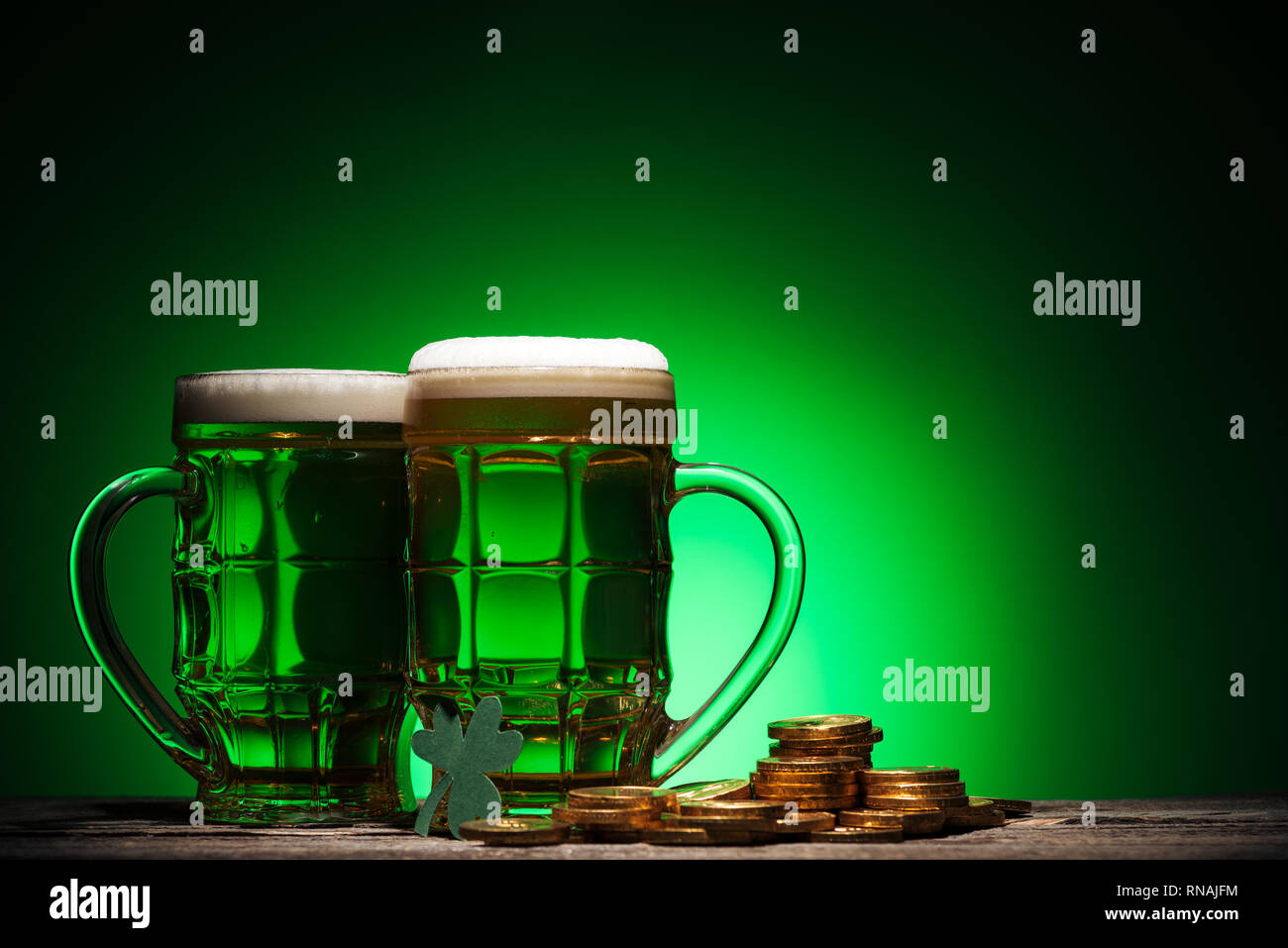 Gläser irisches Bier in der Nähe von Golden Coins auf st patricks day auf grünem Hintergrund Stockfoto