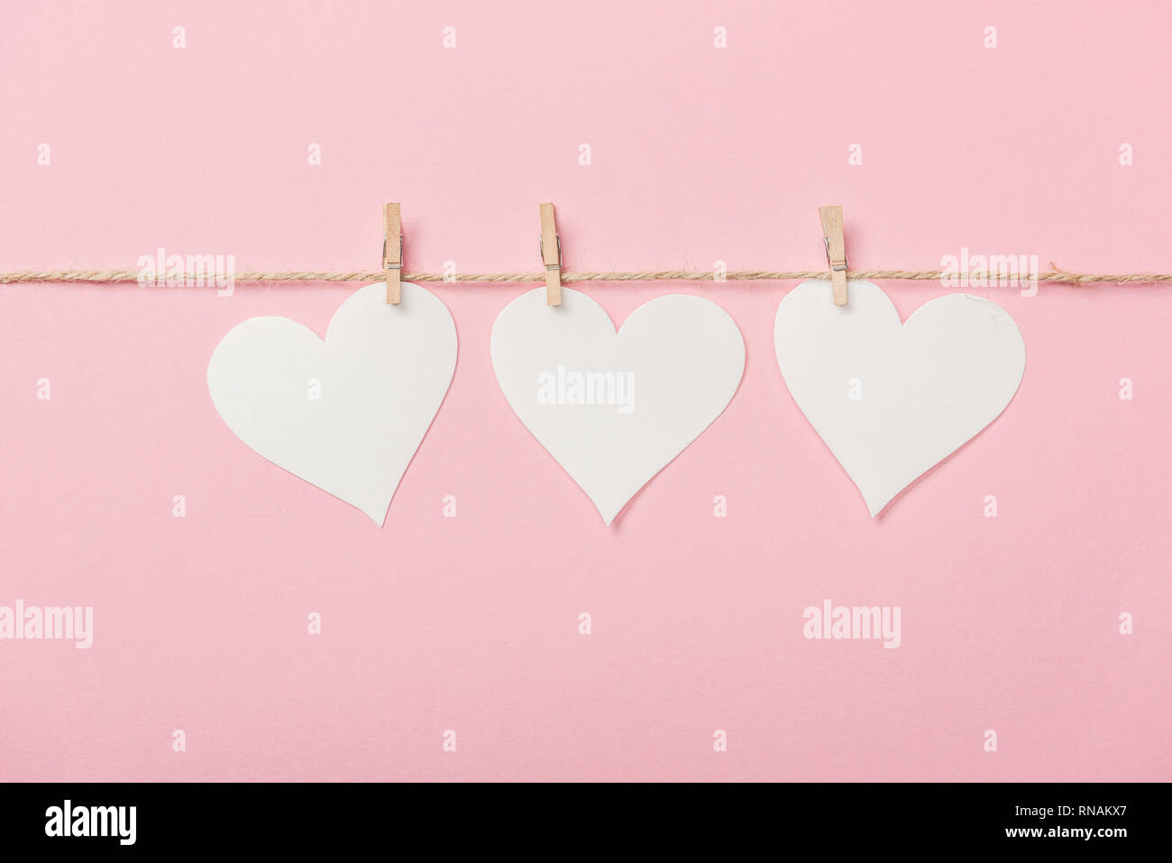 White paper Herzen mit Regelgewinde auf rosa Hintergrund Stockfoto