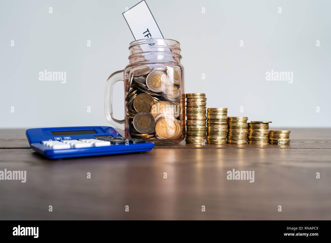 Jar von Münzen mit Taschenrechner angezeigt Einsparungen ein Steuerfreies Sparkonto Stockfoto