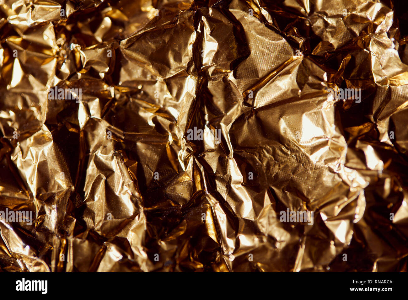 Zerknitterte goldene Folie Blatt mit Twinkles und Schatten Stockfoto