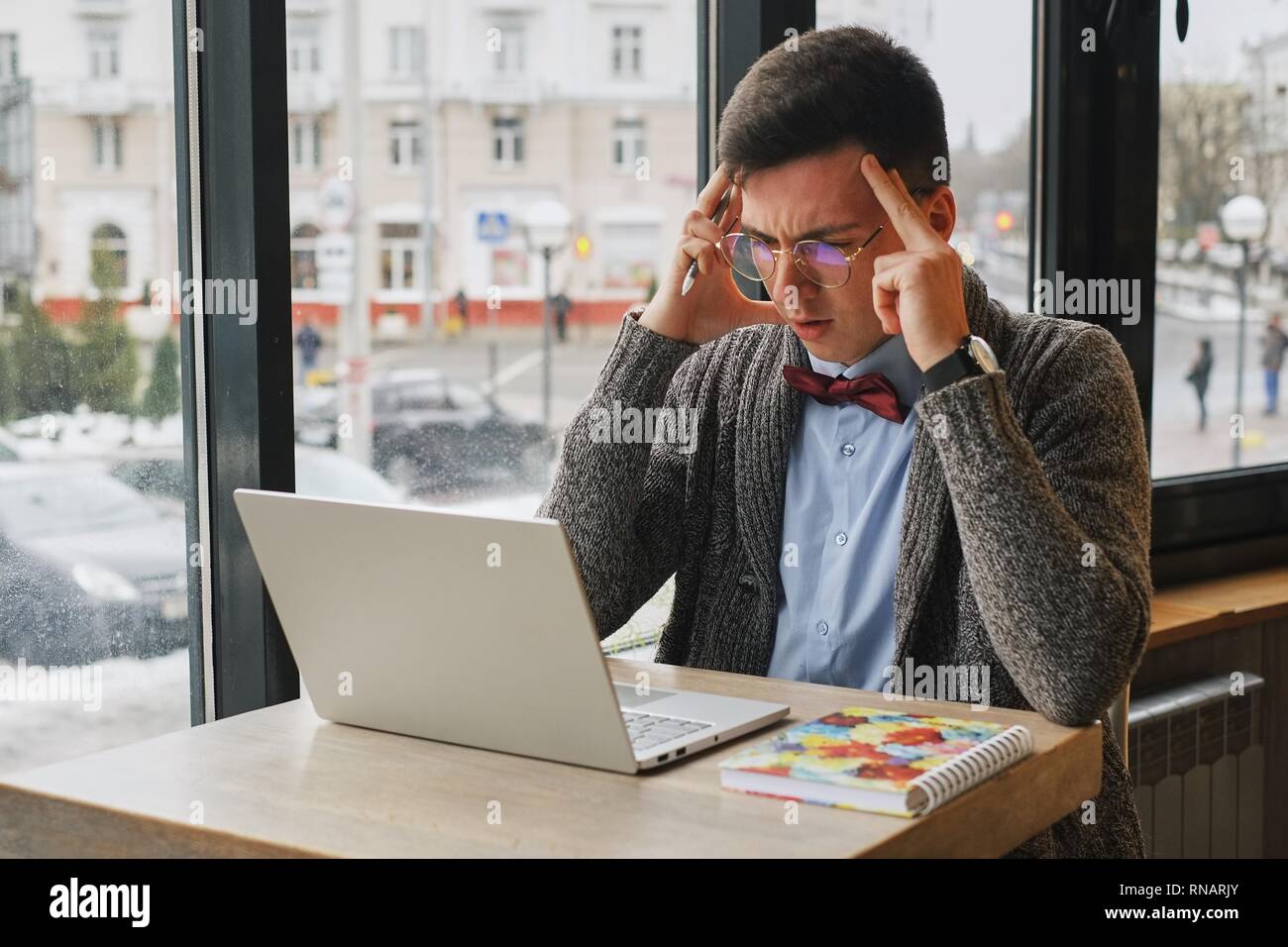 Junge müde, krank, überforderten Mann in formale Abnutzung sitzen vor dem Computer und seine Stirn berühren Stockfoto