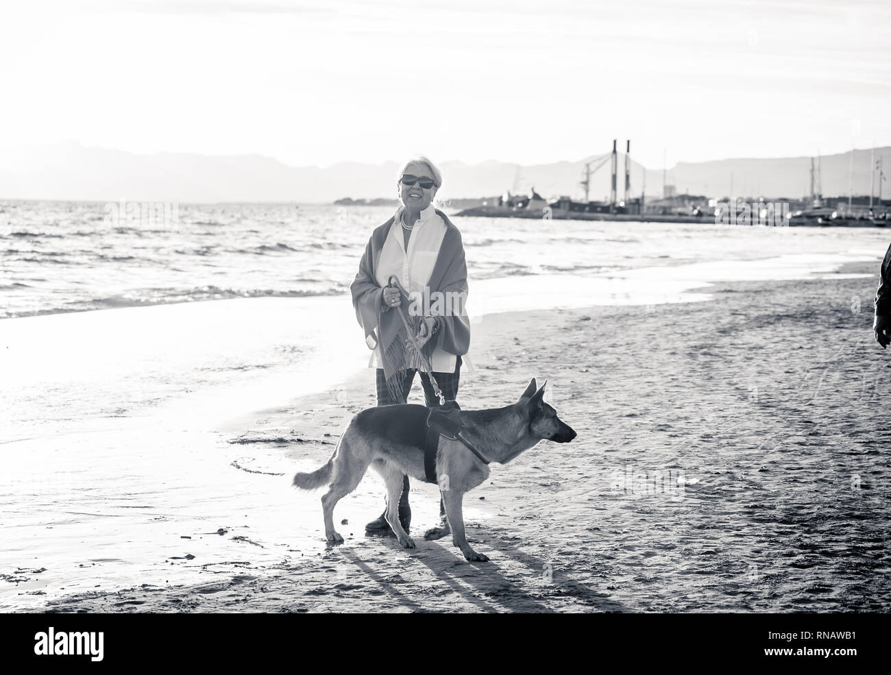 Schönen Ruhestand ältere Frau und pet-deutscher schäferhund Hund wandern entlang der Küste Meer Ozean am Strand in Begleitung Nutzen der Tiere aktiv halten Stockfoto