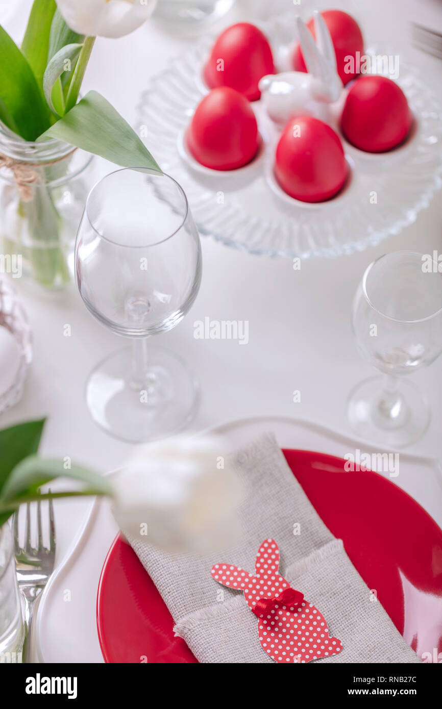 Frohe Ostern. Einrichtung und Einstellung der Ostertisch ist eine Vase mit weißen Tulpen und Gerichte mit roten und weißen Farben. Ostern bunte Eier mit whit Stockfoto