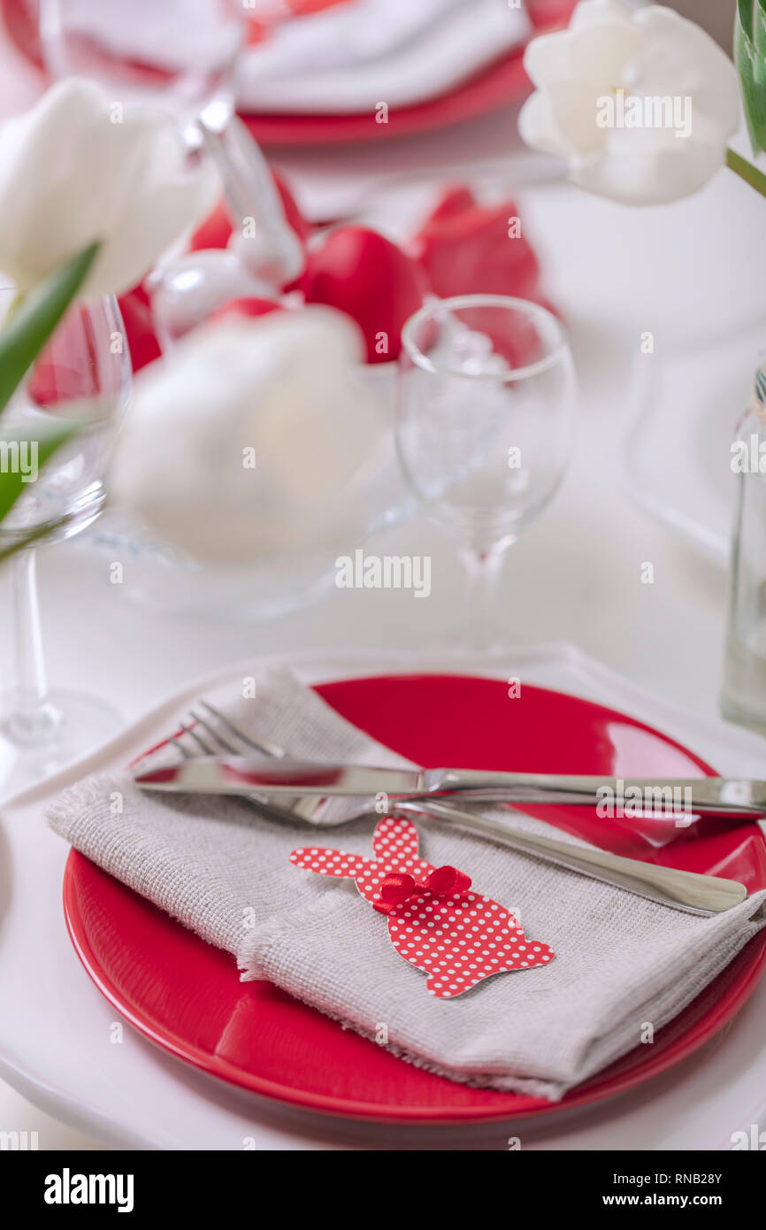 Frohe Ostern. Einrichtung und Einstellung der Ostertisch ist eine Vase mit weißen Tulpen und Gerichte mit roten und weißen Farben. Ostern bunte Eier mit whit Stockfoto