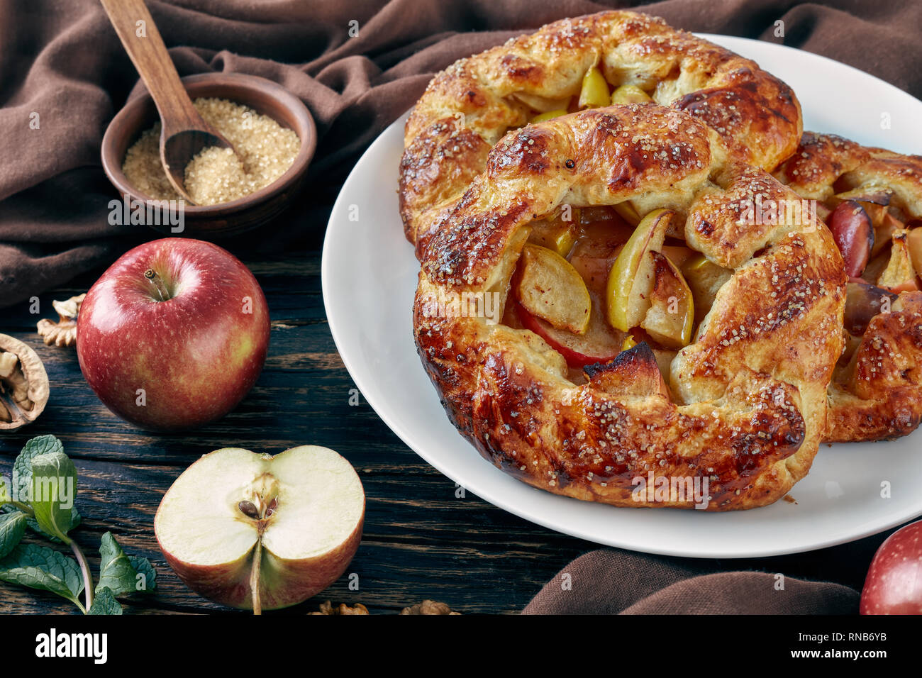 In der Nähe von köstlichen Öffnen Sie Apple Pies, Galettes mit Apfelscheiben mit Zucker auf einem weißen Teller bestreut. apple, Zimtstangen, brauner Zucker und Kit Stockfoto