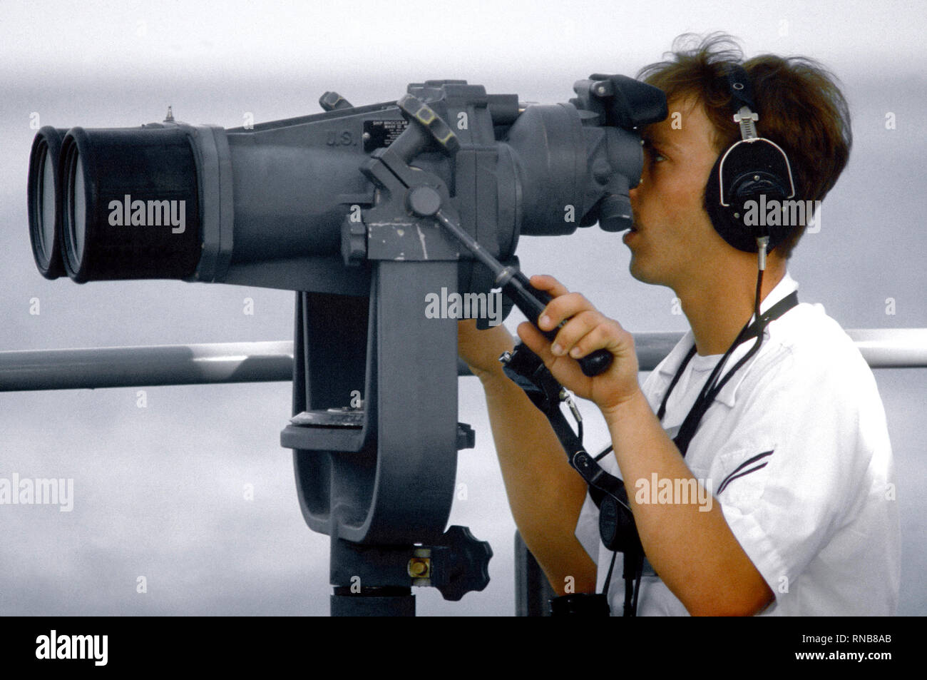 1980 - der Seemann Lehrling verwendet Fernglas des Schiffes während der Übung Unitas XXI. Stockfoto