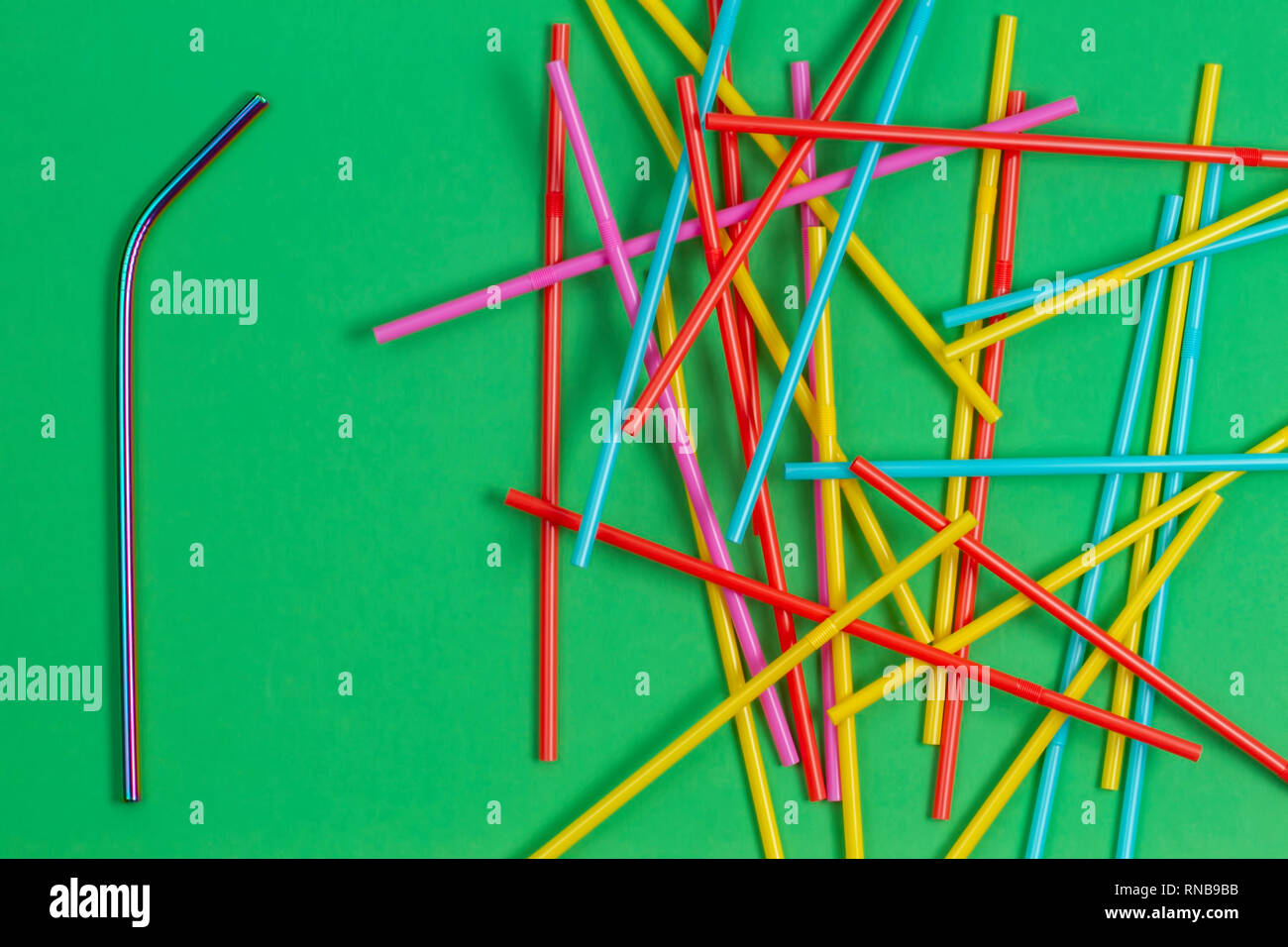 Edelstahl wiederverwendbare Trinkhalm mit vielen bunten Plastik Strohhalme auf grünem Hintergrund Stockfoto