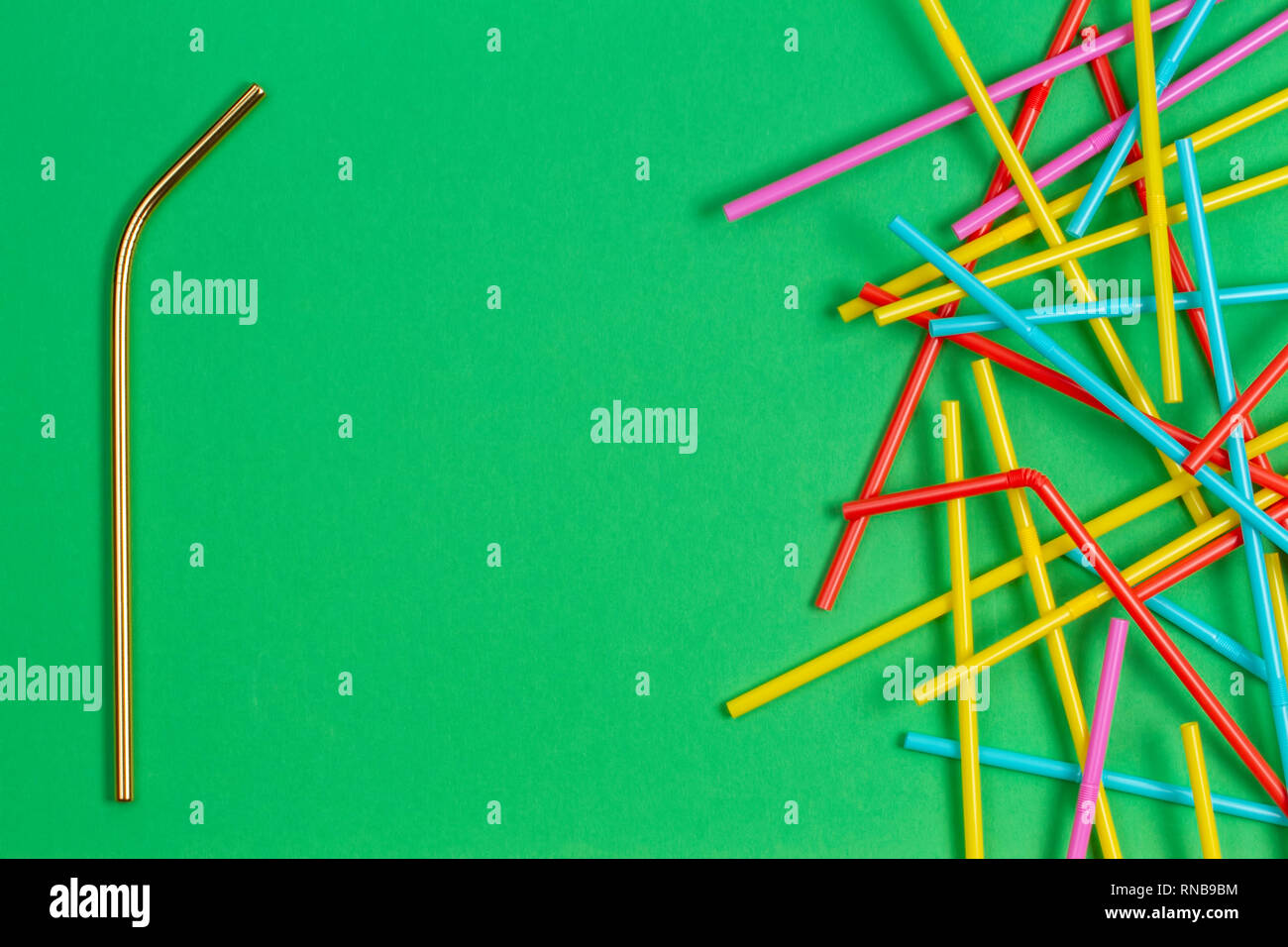Edelstahl wiederverwendbare Trinkhalm mit vielen bunten Plastik Strohhalme auf grünem Hintergrund Stockfoto
