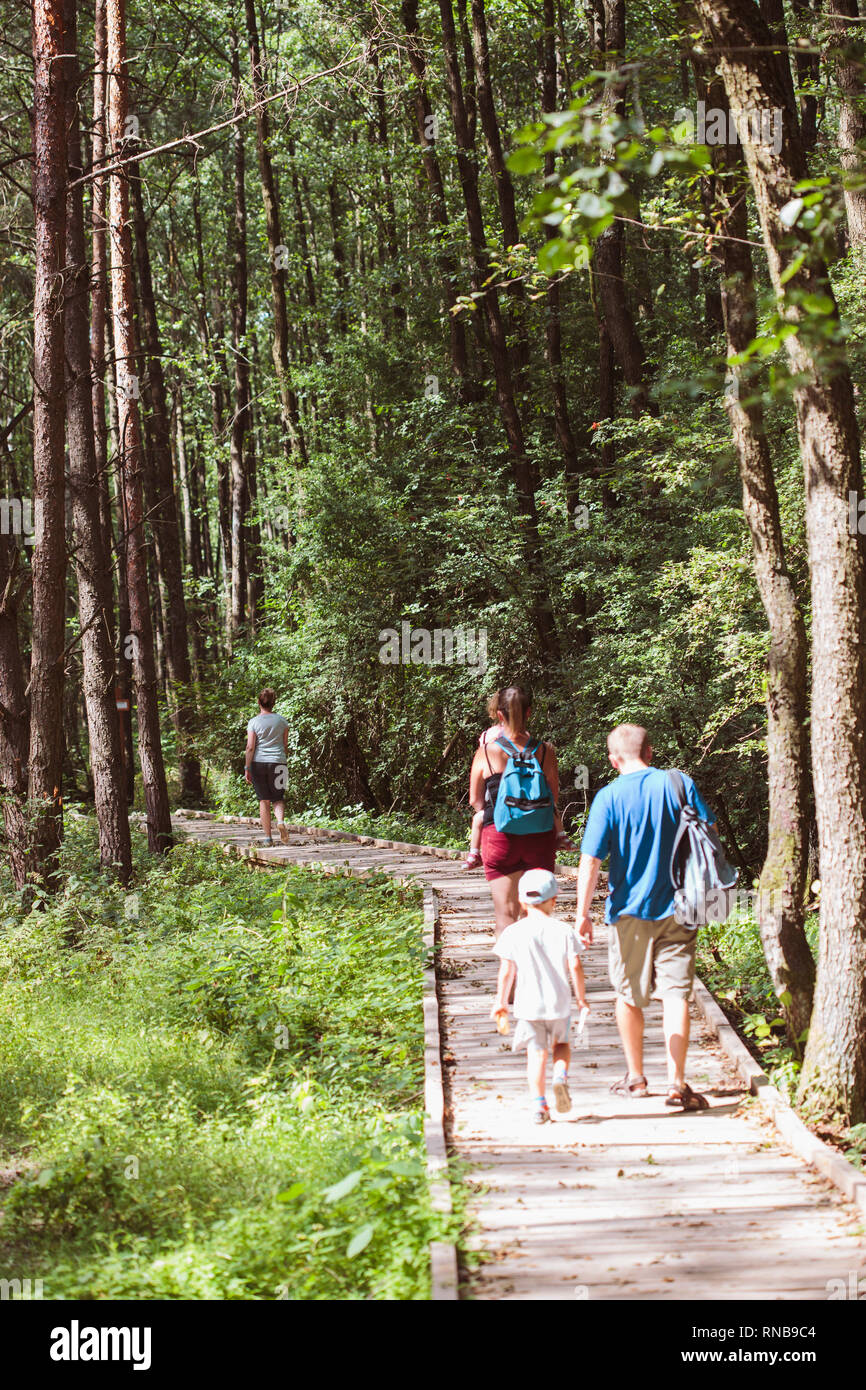 Familie gehen, ein Weg in den Wald. Mutter, Vater, Jungen und Mädchen Zeit miteinander zu verbringen, Urlaub in der Natur Stockfoto