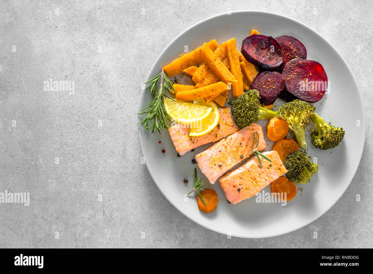 Gebratener Lachs mit Gemüse. Gegrilltes Fischfilet mit Pommes frites auf Teller, Ansicht von oben Stockfoto