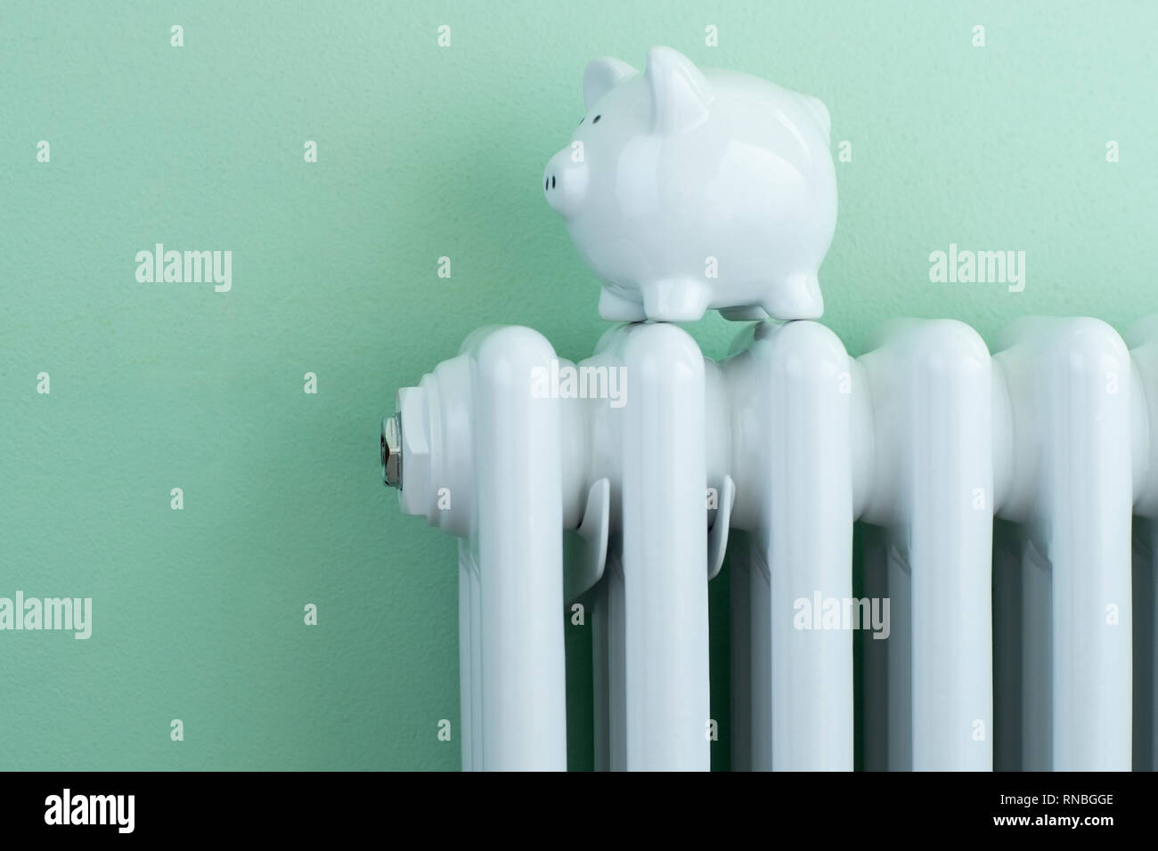 Piggy Bank ausgeglichen am Kühler zu Energiekosten veranschaulichen Stockfoto