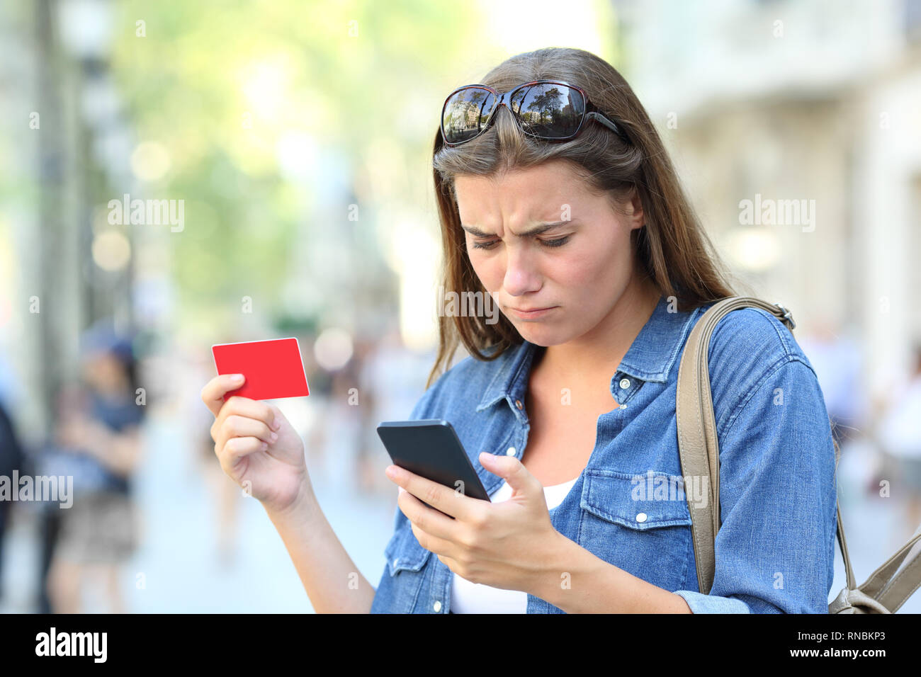 Besorgt Mädchen in problem Bezahlung Online mit Kreditkarte oder Smart Phone auf der Straße Stockfoto