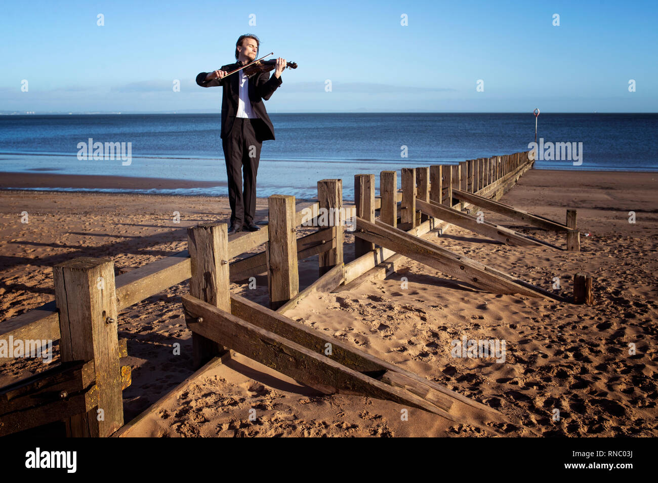 Musiker und Komponist Daniel Safford, aus Philadelphia, USA, spielt die Il Mare Violine, die aus Treibholz, auf Portobello Beach, Edinburgh, vor seiner Leistung an Schottlands International Marine Konferenz in Glasgow in dieser Woche. Stockfoto