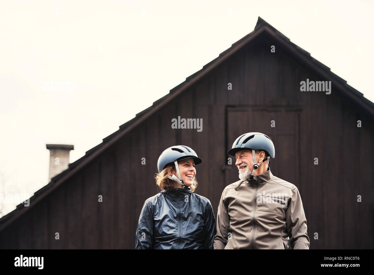 Active Senior Paar mit Fahrrad Helme stehen draußen vor einem Haus. Stockfoto