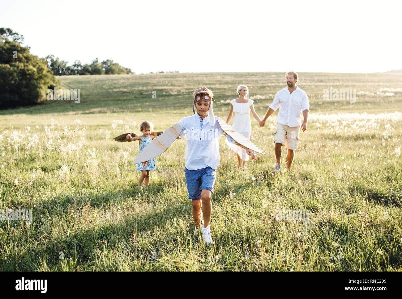 Junge Familien mit kleinen Kindern das Spielen auf einer Wiese in der Natur. Stockfoto