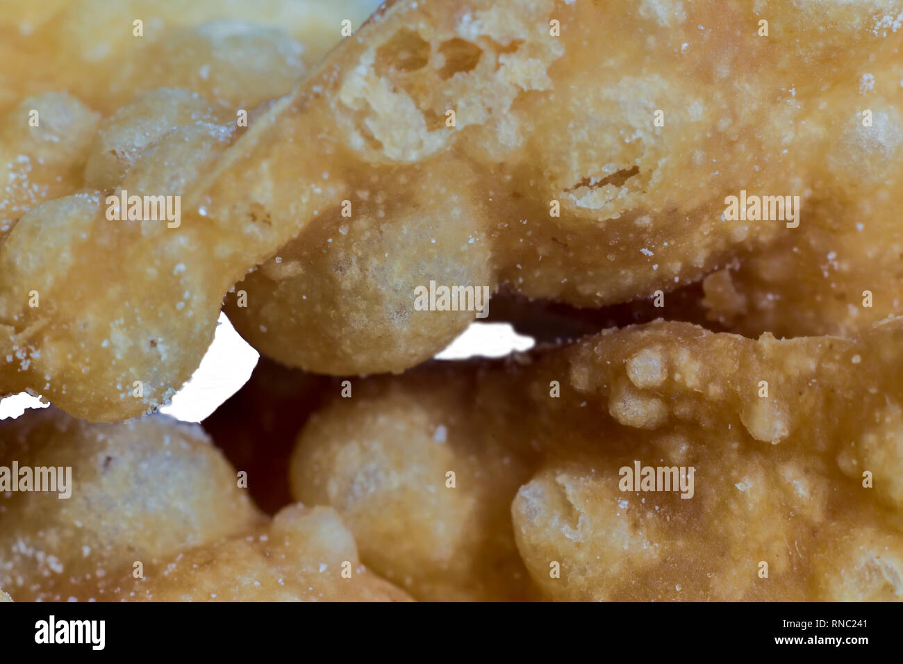 Macrophoto. Europäischen dessert Angel Wings. Interessante Textur von frittierte Teig Streifen mit mit einem Loch in der Mitte. Über Gebäck, Süßigkeiten. Stockfoto