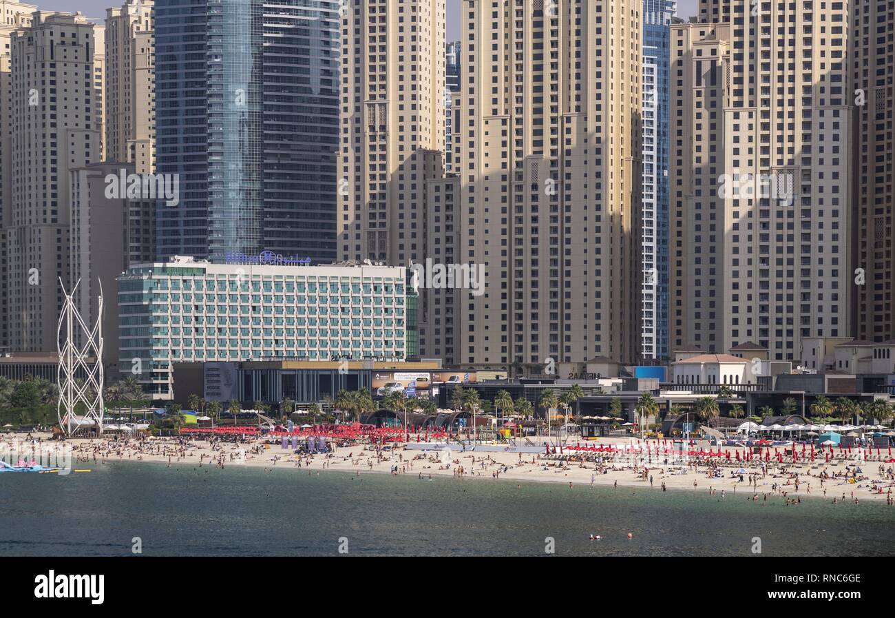 Der Strand ist der Name des beliebten Strandabschnitt in Dubai, hinter der sich die imposante Wolkenkratzer von der exklusiven Marina Bay Viertel steigen. Der öffentliche Strand mit feinem Sand, Freizeitaktivitäten und Restaurants. (15. Januar 2019) | Verwendung weltweit Stockfoto