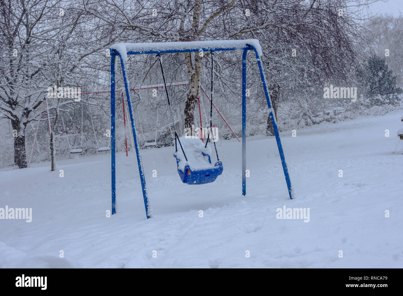 Blau Kinder Schaukel für Behinderte in einer verschneiten Spielplatz Stockfoto