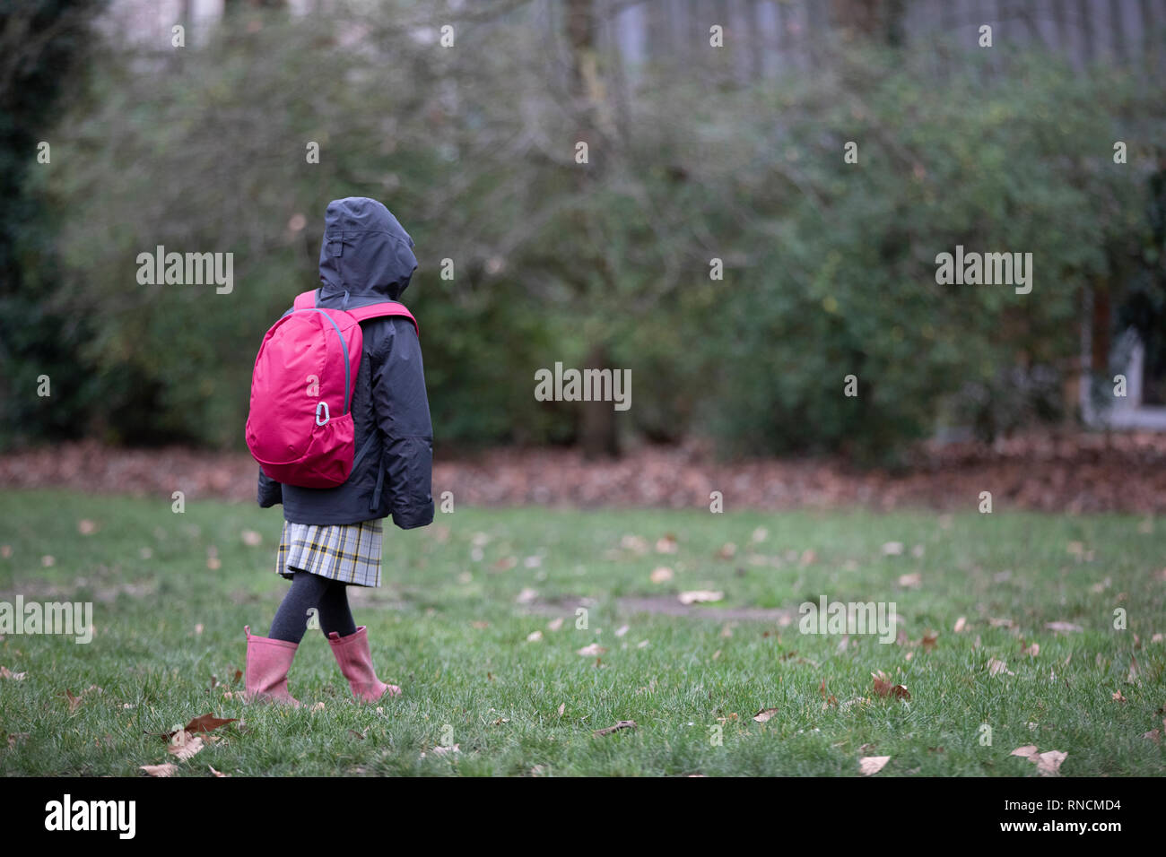 Grundschule Mädchen allein gehen über Park auf dem Weg zur Schule Stockfoto