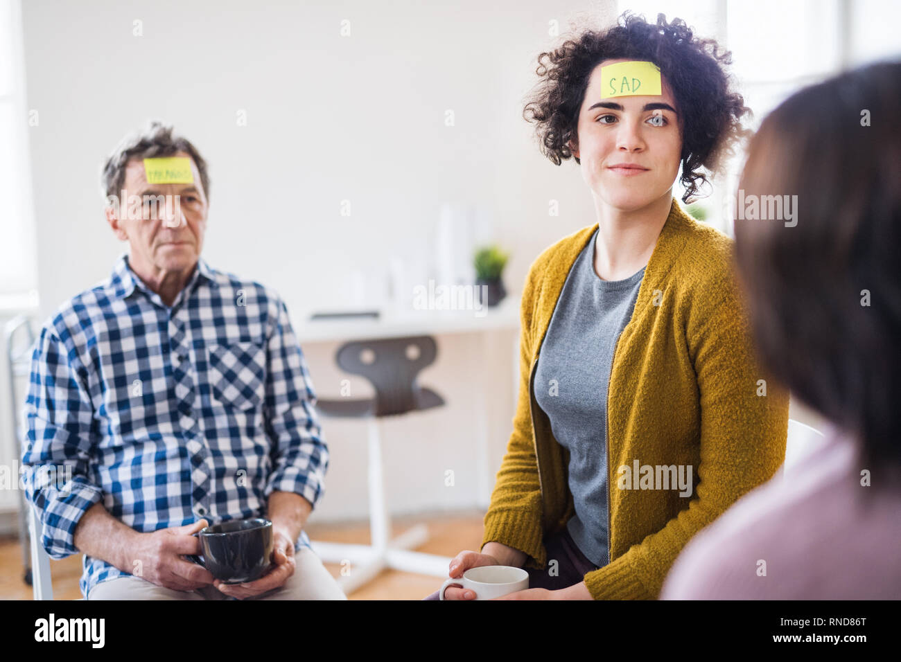 Männer und Frauen im Kreis während der Gruppe Therapie sitzen, Haftnotizen auf der Stirn. Stockfoto