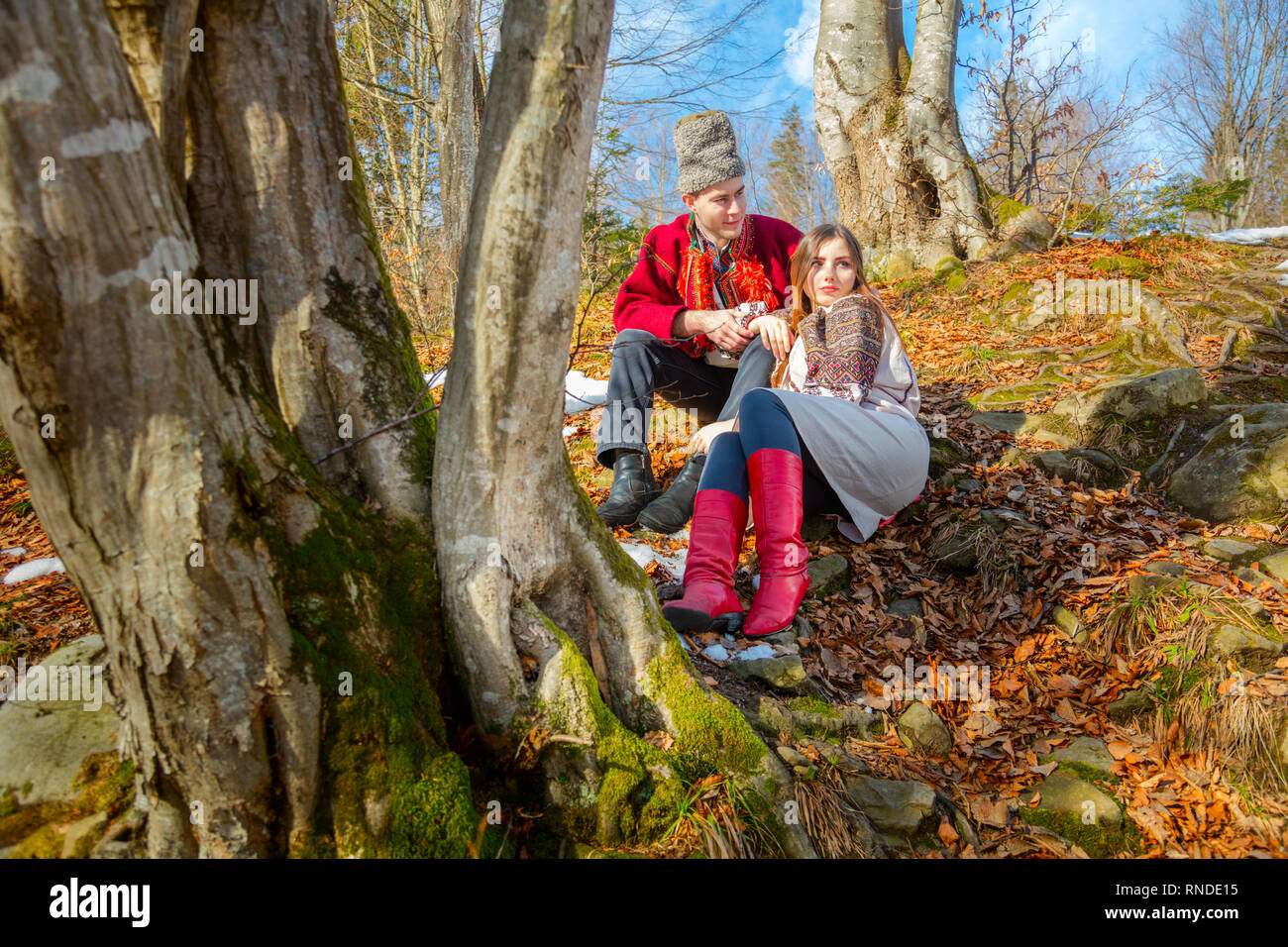 Junges Paar mit traditioneller Kleidung, die auf den natürlichen Wald in Karpaten - Verlieben, Jugend und Feder sonnigen Tag Stockfoto