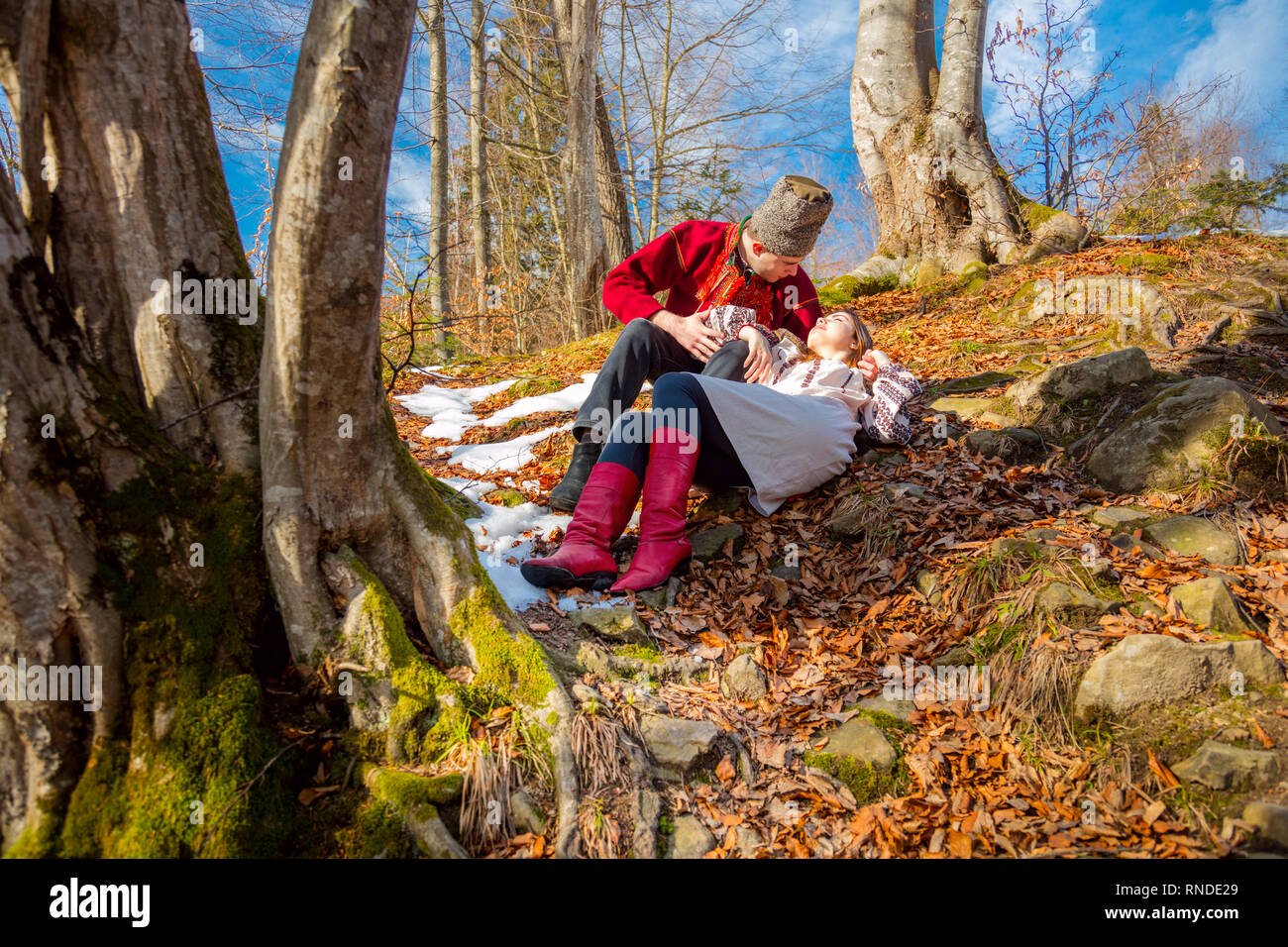 Junges Paar mit traditioneller Kleidung, die auf den natürlichen Wald in Karpaten - Verlieben, Jugend und Feder sonnigen Tag Stockfoto