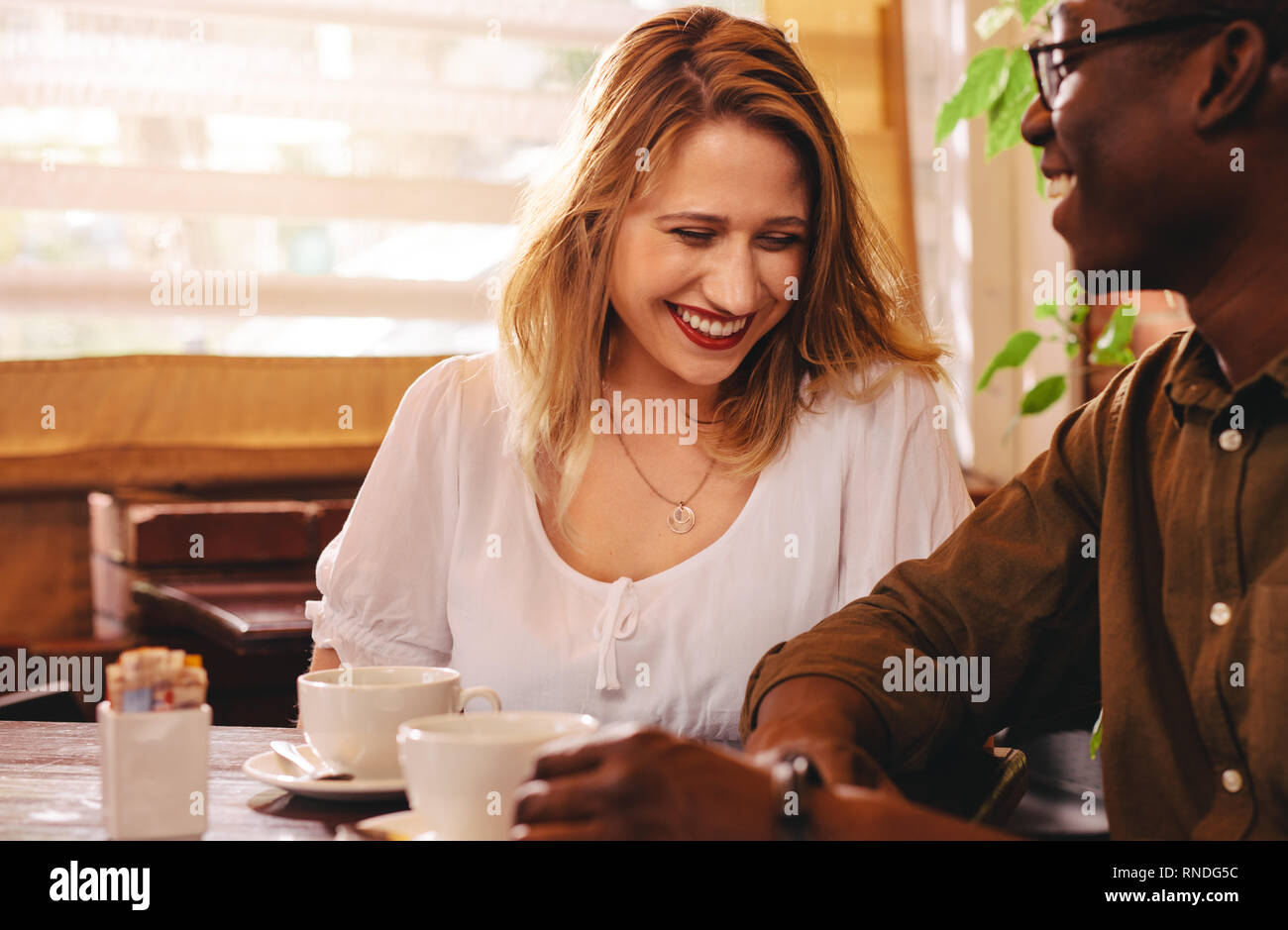 Fröhliche Frau im Cafe sitzen mit ihrem Freund. Multi-ethnischen Paar zusammen im Coffee Shop. Stockfoto