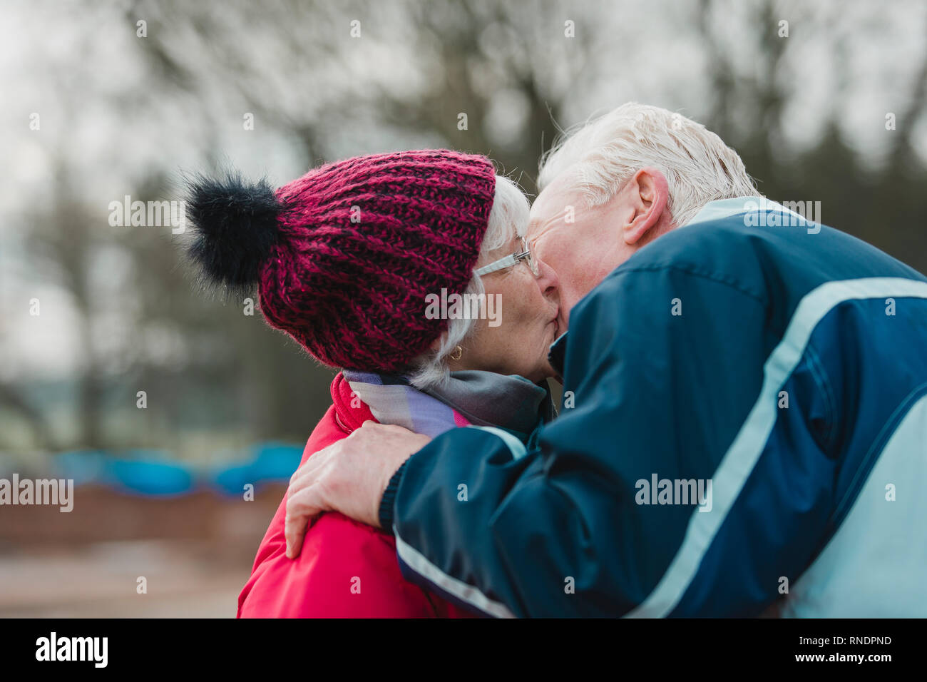 Älterer Mann küsste seine Frau außerhalb des eigenen im Winter. Stockfoto