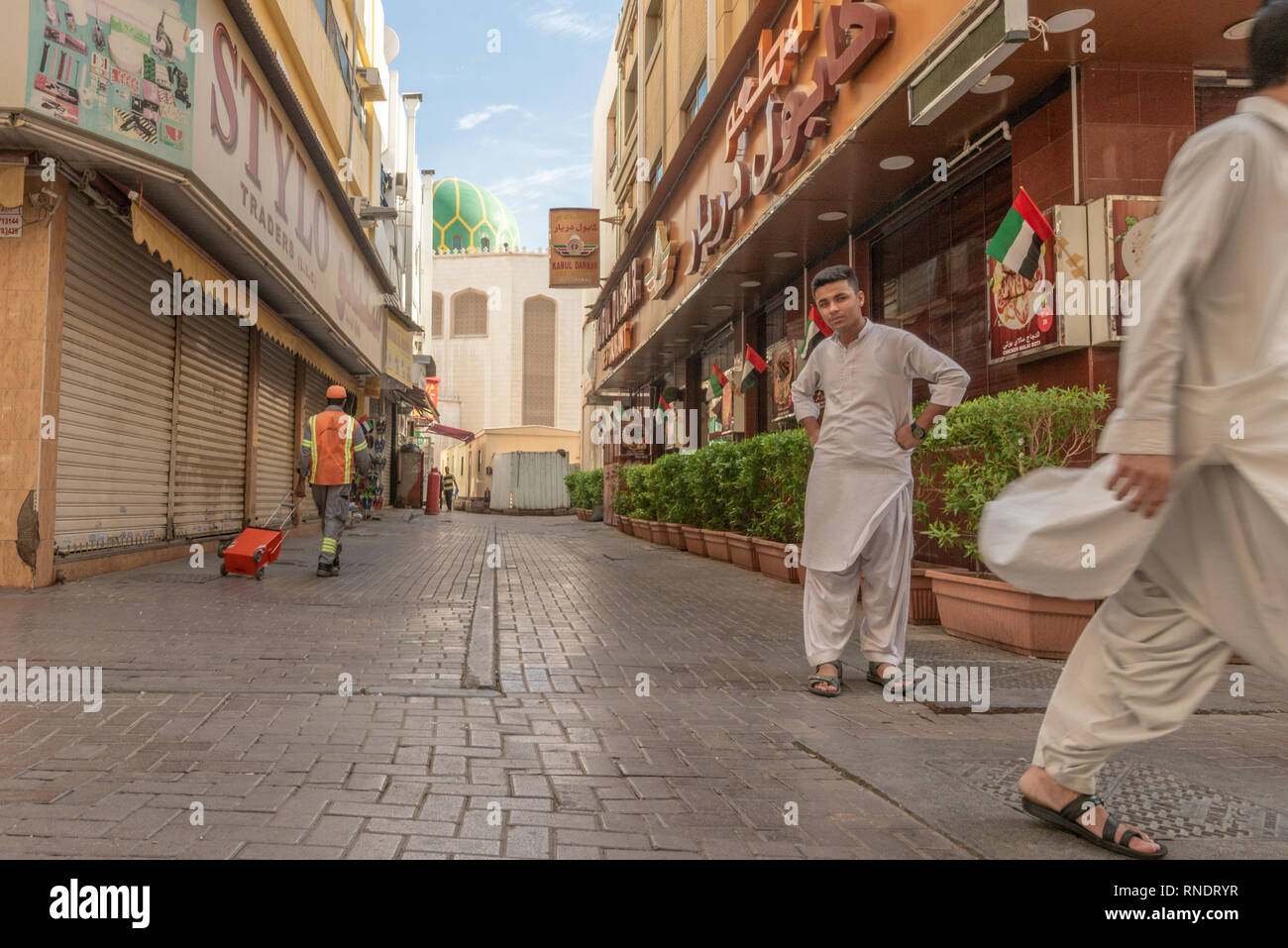 Pakistanische Männer wandern und starrte auf die Kamera in einer ruhigen Straße des beliebten und ethnischen Stadtteil Deira in Dubai, Vereinigte Arabische Emirate, Stockfoto