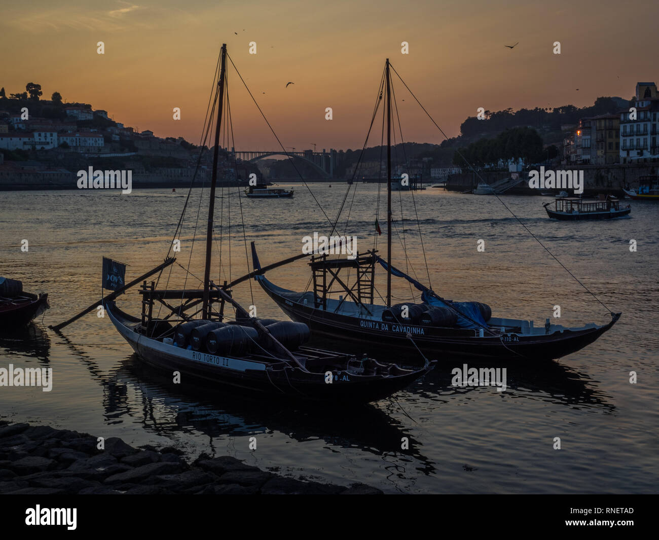 Ein Sonnenuntergang über den Fluss Douro bei Ebbe in Porto mit einem Paar von zwei 2 Yachten Quinta da Cavadinha und Rio Torto II in Silhouette und Vogel fliegen Stockfoto