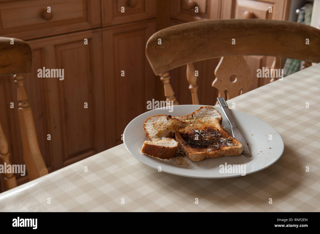 Gehetzt unvollendete Marmelade auf Toast zum Frühstück am Tisch mit einigen Lesestoff und Schmerzmittel Tabletten Stockfoto