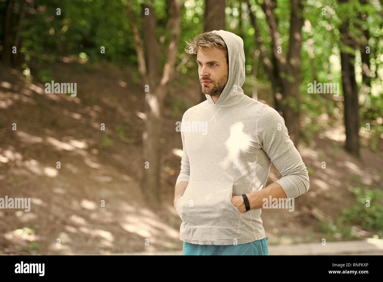 Sportler Training mit schrittzähler Gadget. Athlet mit Borsten mit Fitness tracker oder Schrittzähler. Sport gadget Konzept. Mann Athlet auf strengen Gesicht mit Sport Ausrüstung posiert, Natur Hintergrund. Stockfoto