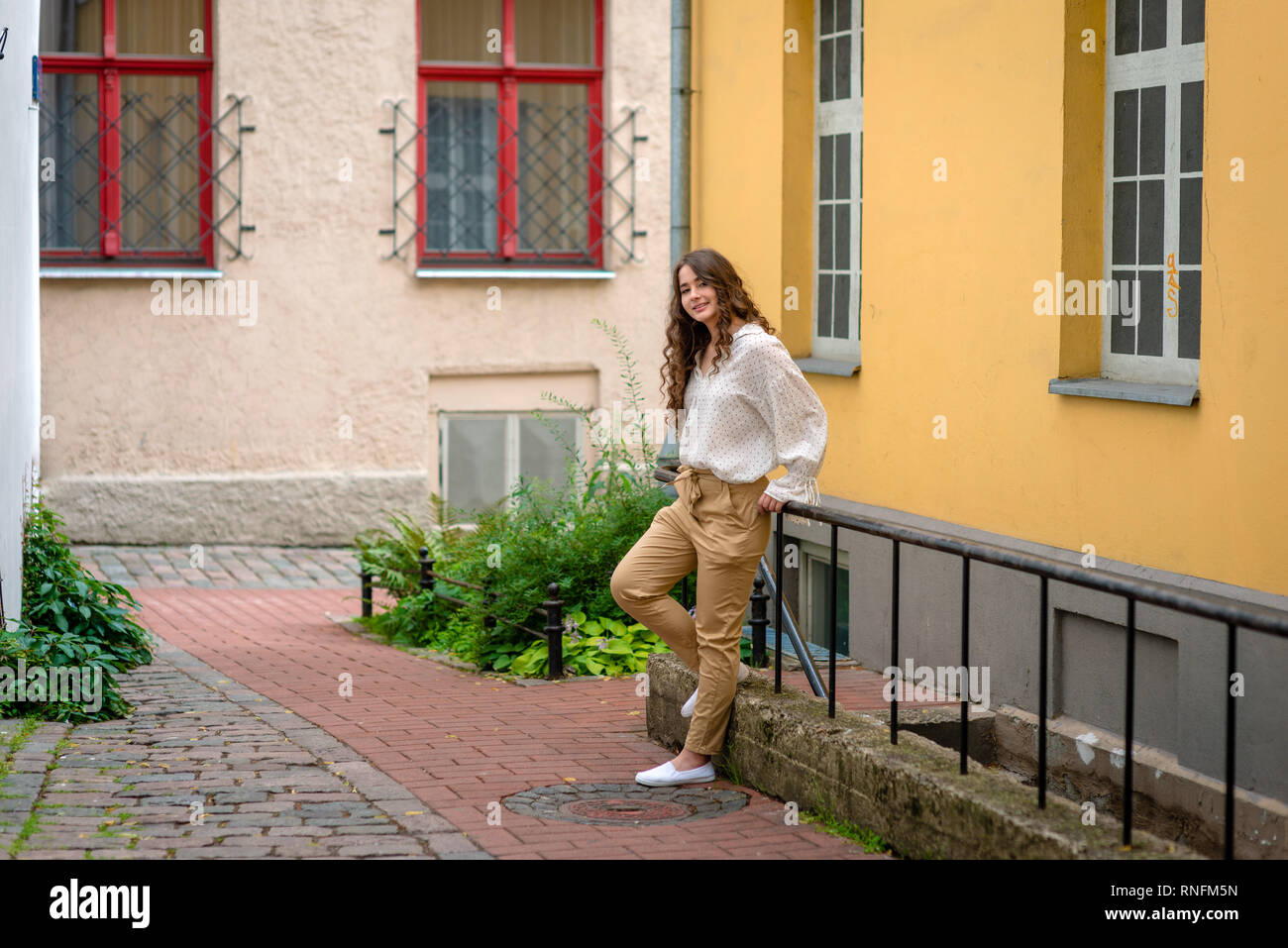 Eine junge, hübsche, dunkelhaarige Frau, die sich im Untergeschoss Treppe in einem alten Haus Hof. Stockfoto