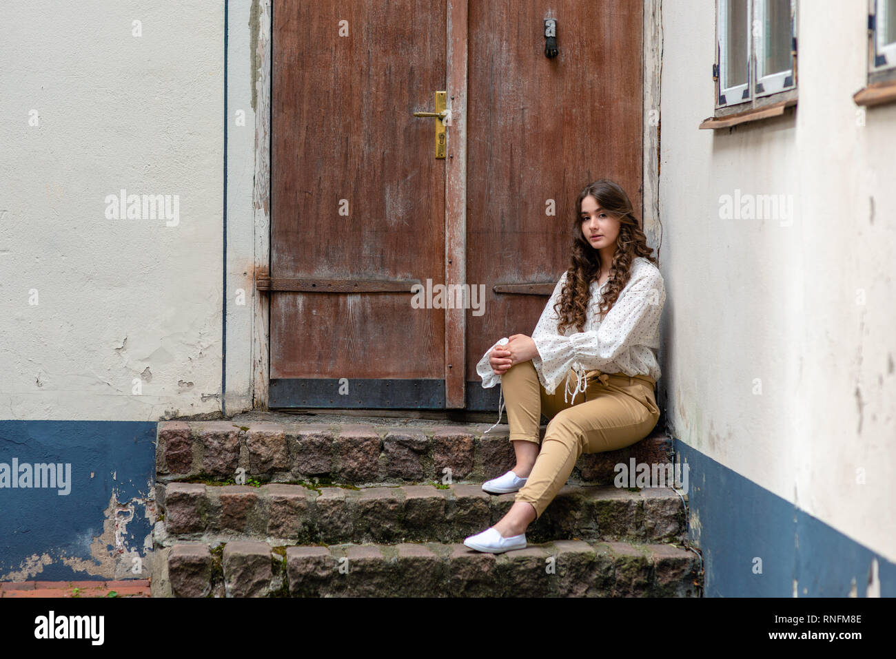 Eine junge, hübsche, dunkelhaarige Frau sitzt auf einem alten Haus Treppen. Kopieren Sie Platz. Stockfoto