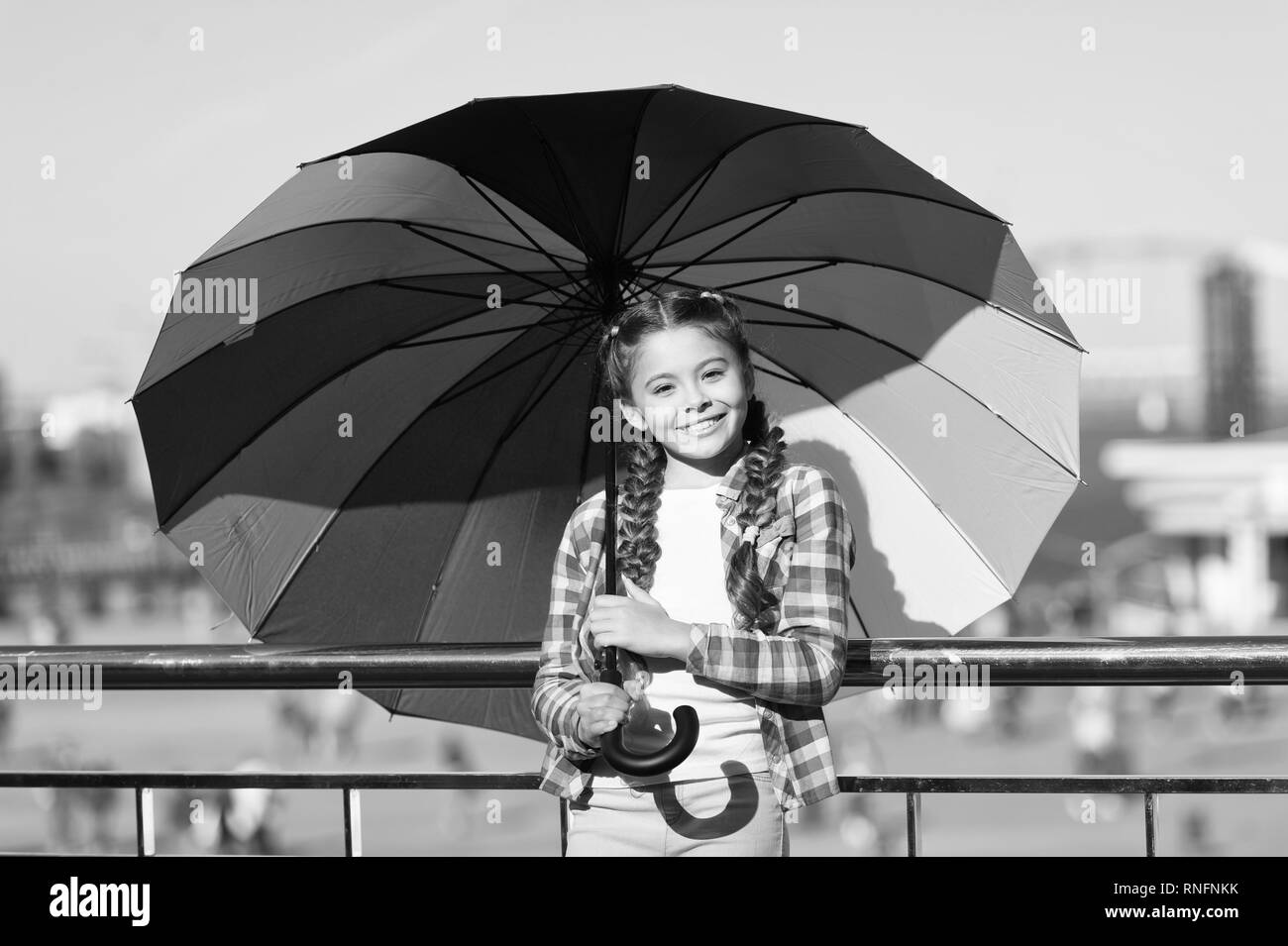 Kleine hübsche Mädchen mit bunten Regenschirm. Mädchen auf der Brücke. Ausblenden von Sun mit Regenschirm. Helle Farbtöne von Mädchen, fröhliche Stimmung. Warten auf Regen unter dem Dach. Stockfoto