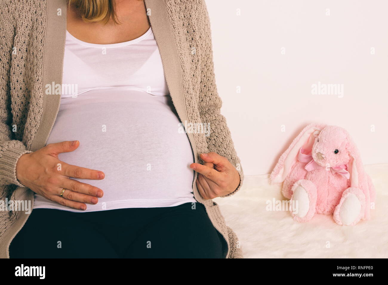 Weiß schwangere Frau mit Bauch zu rosa Plüsch Bunny Closeup Stockfoto