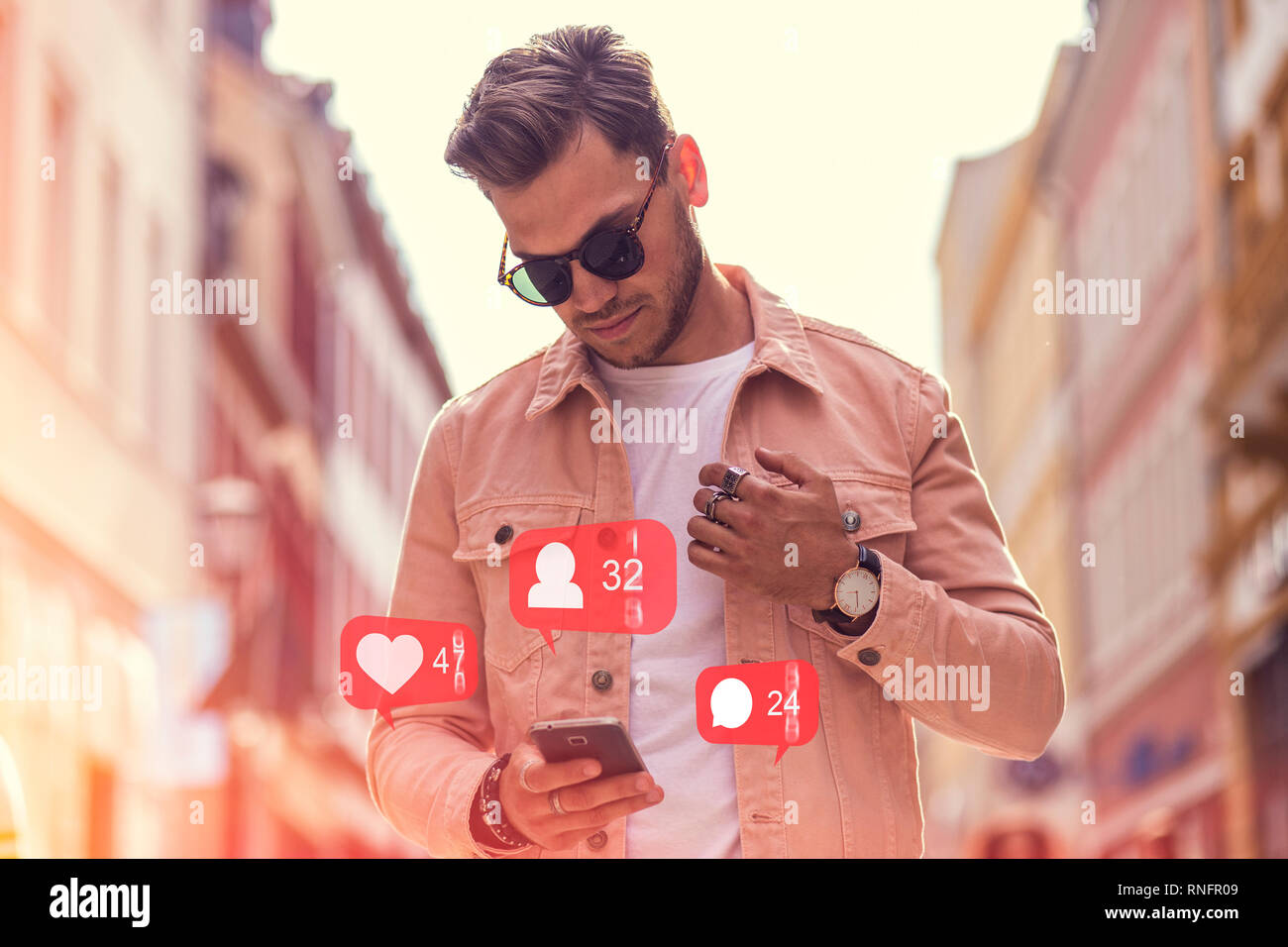 Junge Modische erwachsenen Mann mit Social Media auf dem Smartphone auf der Straße - Wie, Follower, Kommentar Symbole und Zahlen Stockfoto