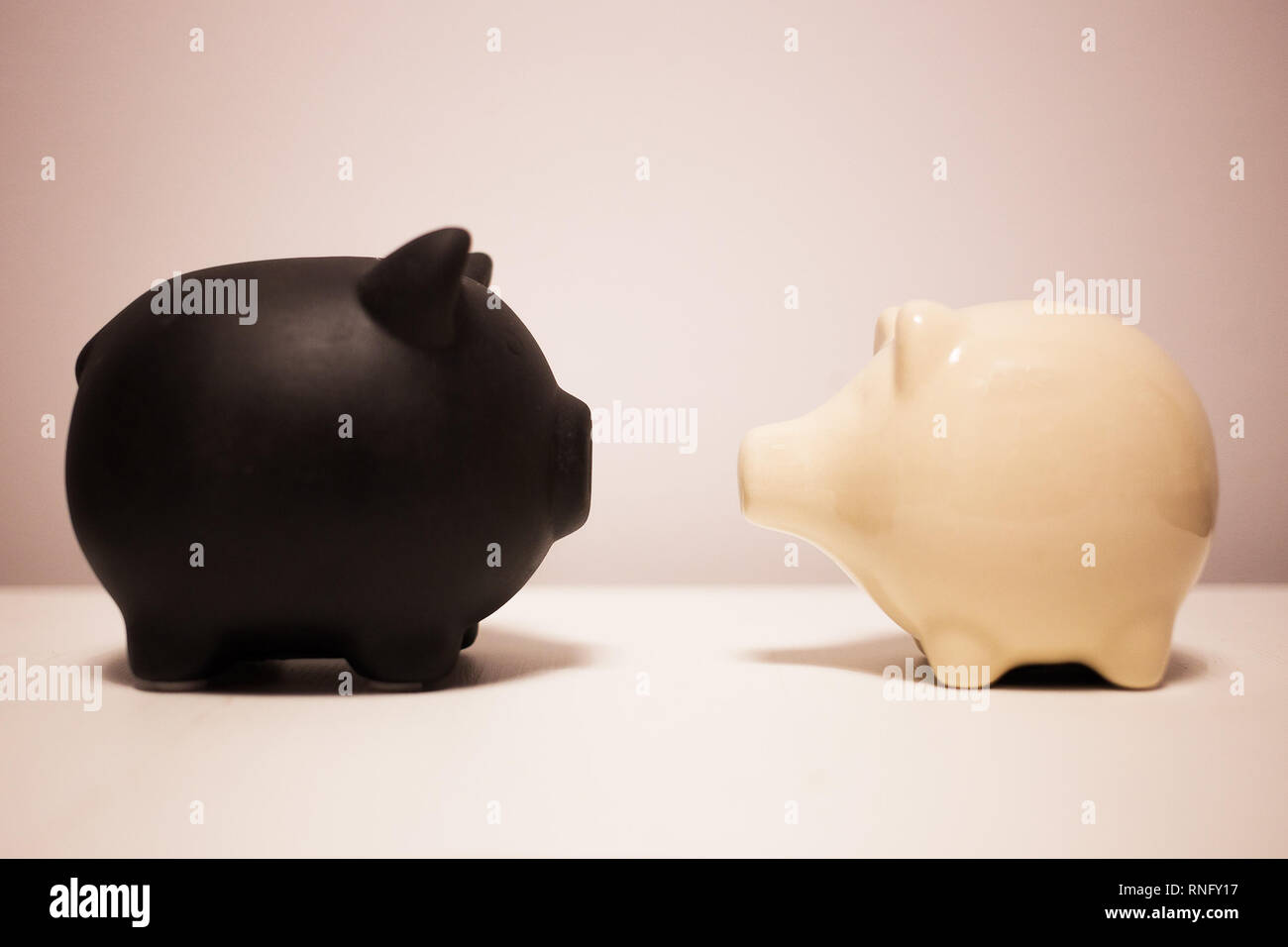 Schwarze und weiße Sparschwein auf der Ebene Hintergrund, Konzept von Schulden und Einsparungen Stockfoto