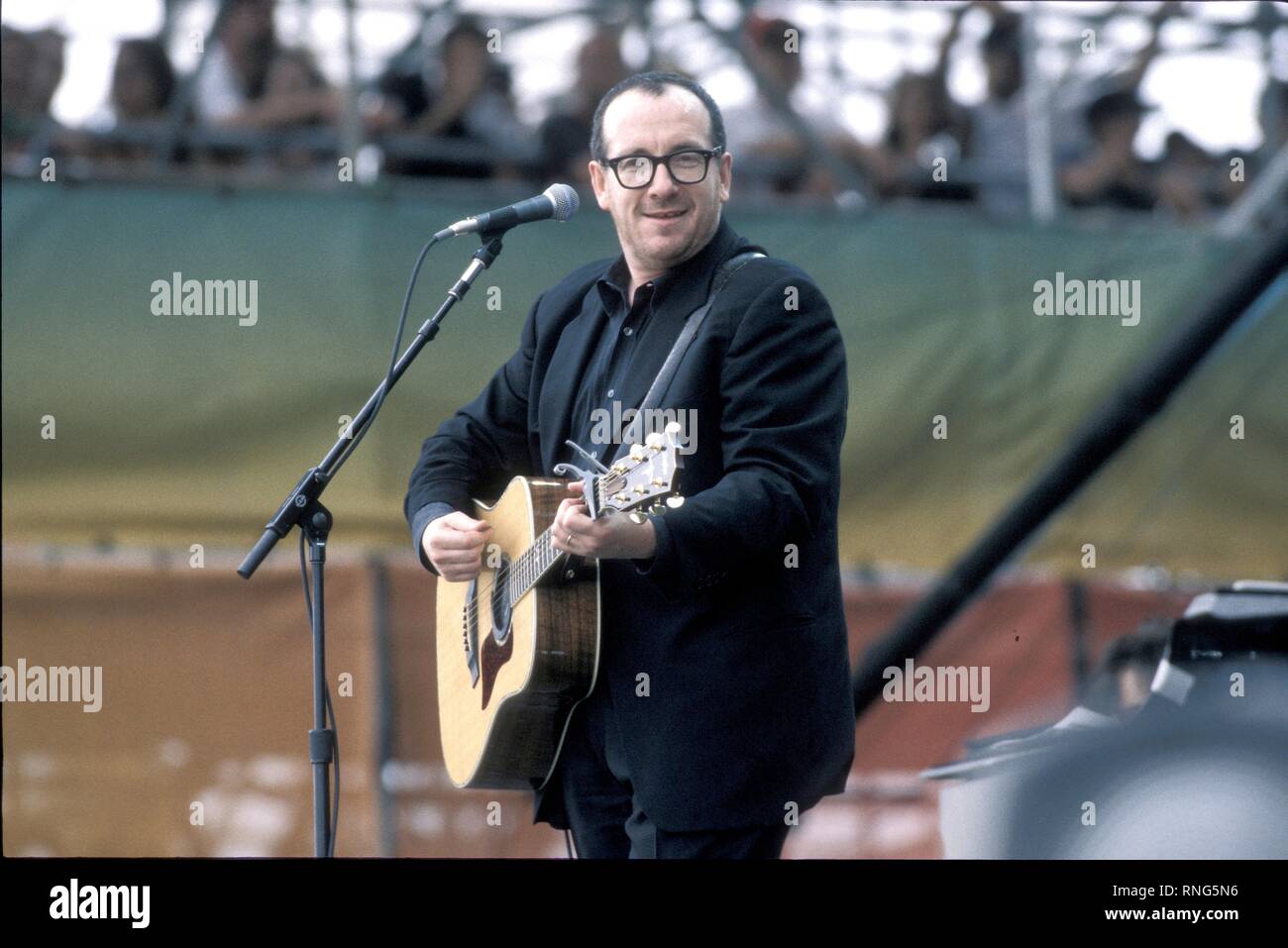 Sänger und Songwriter Elvis Costello ist zeigen, Gitarre spielen und singen auf der Bühne in Woodstock '99. Stockfoto Sänger und Songwriter Elvis Costello ist zeigen, Gitarre spielen und singen auf der Bühne in Woodstock '99. Stockfoto